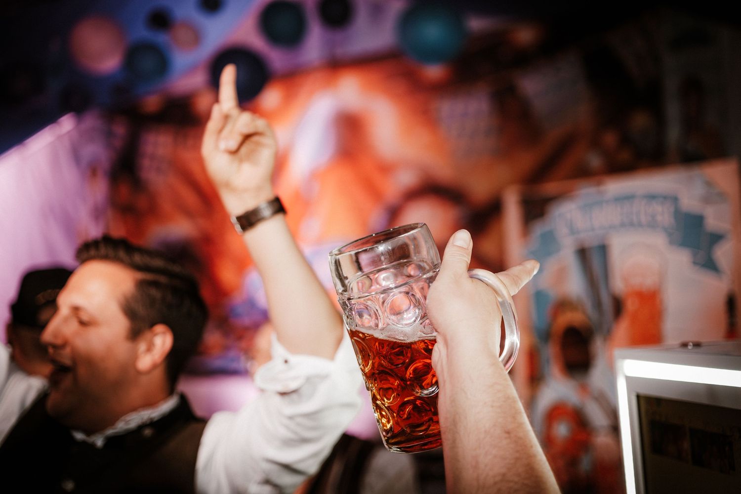 People enjoying drinks at a nightclub with colorful lighting and party atmosphere.