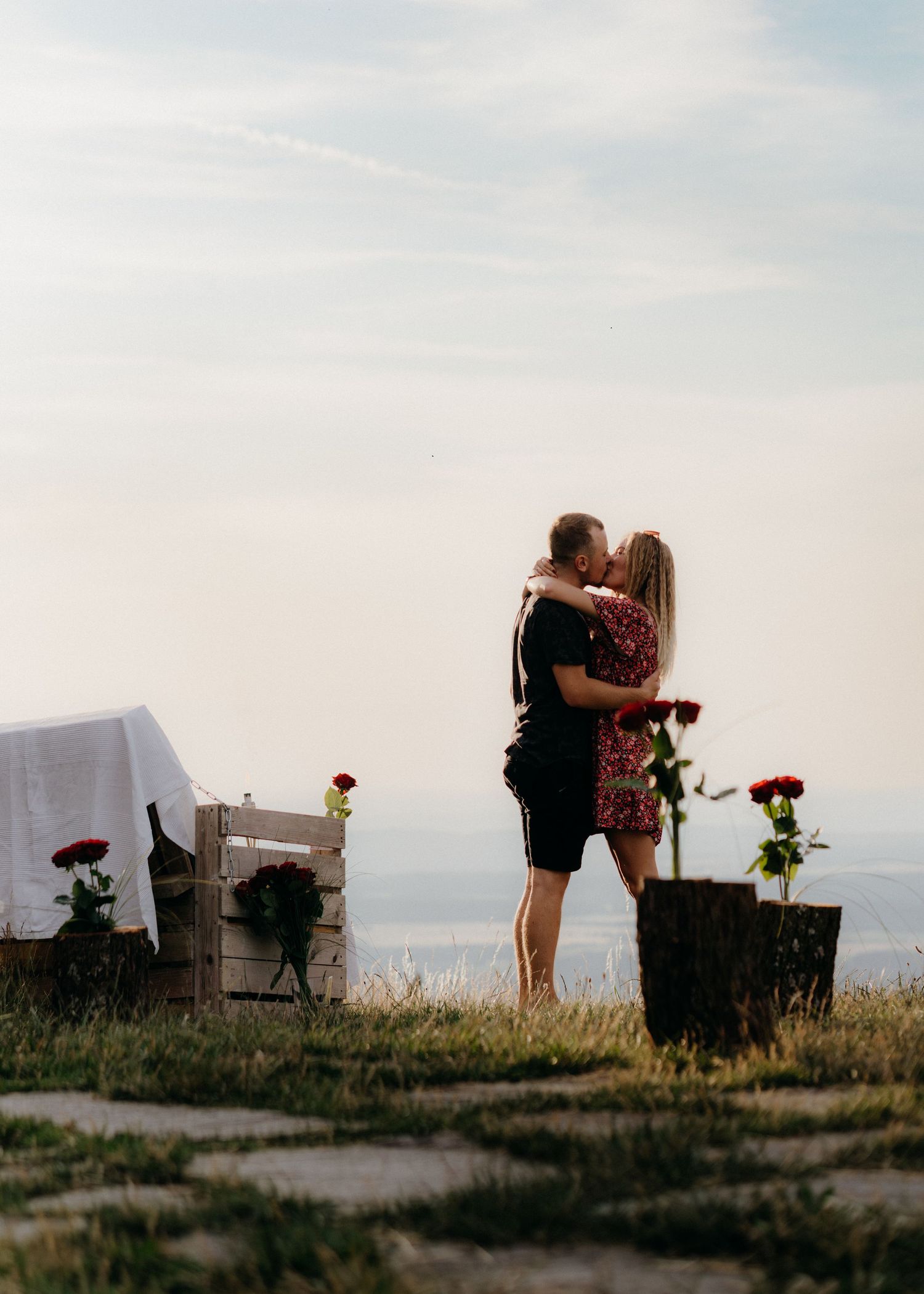 A series of silhouettes against a sunset sky show two people embracing on a hilltop with roses in the foreground.