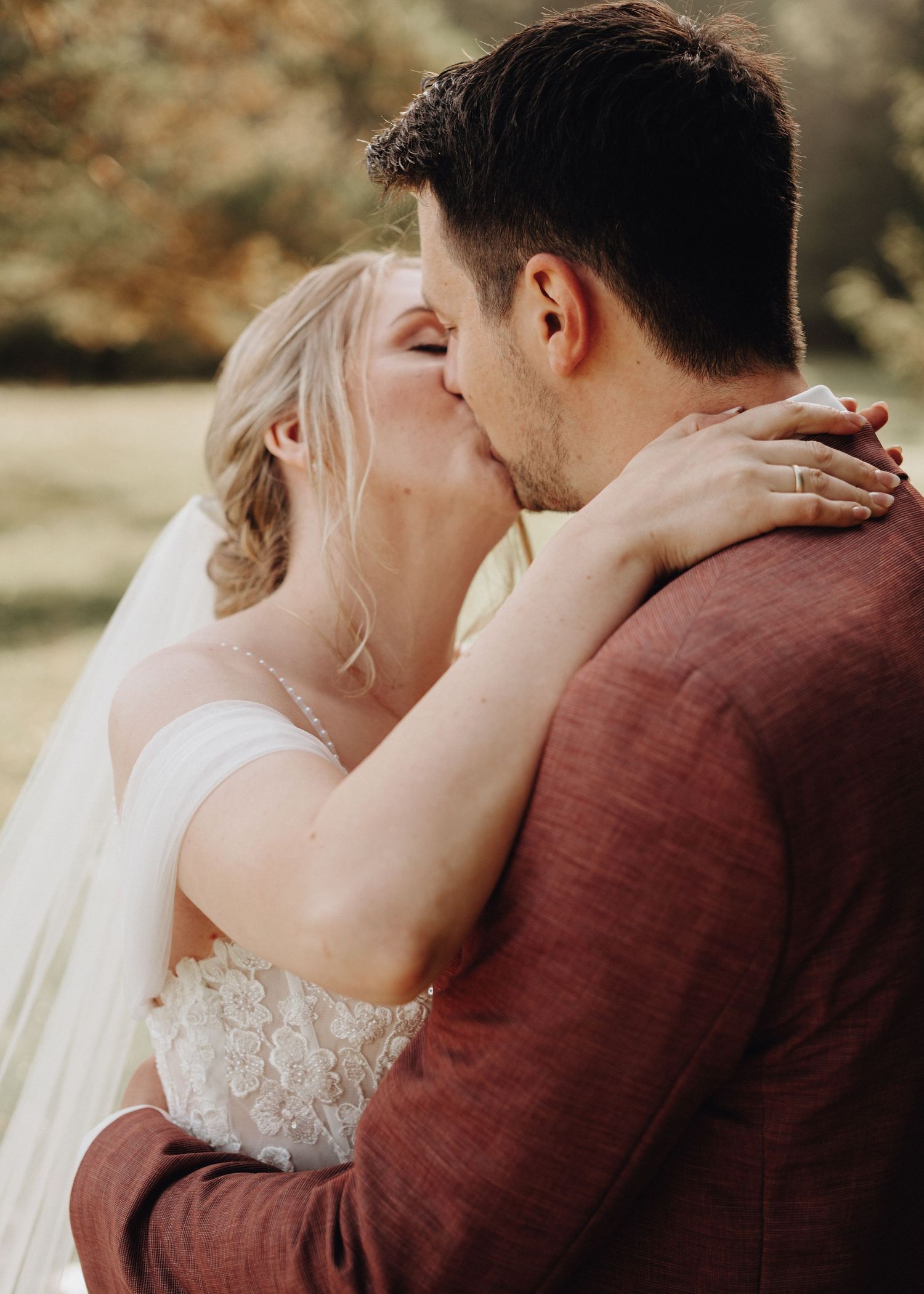 Romantic outdoor wedding portraits featuring burgundy suit details and intimate moments.