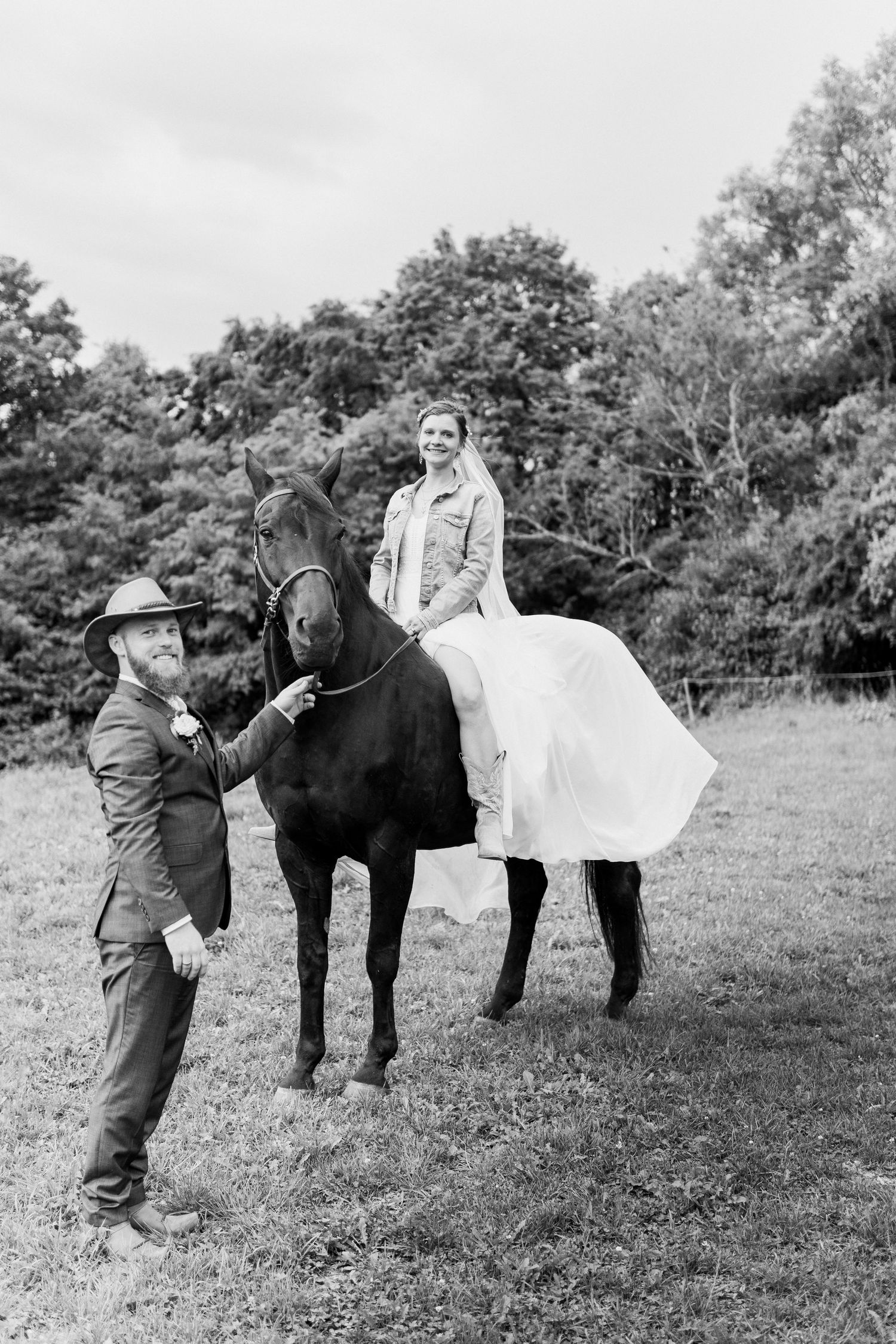 A sequence of black and white photos showing a person in a dress sitting on a black horse in a grassy field.