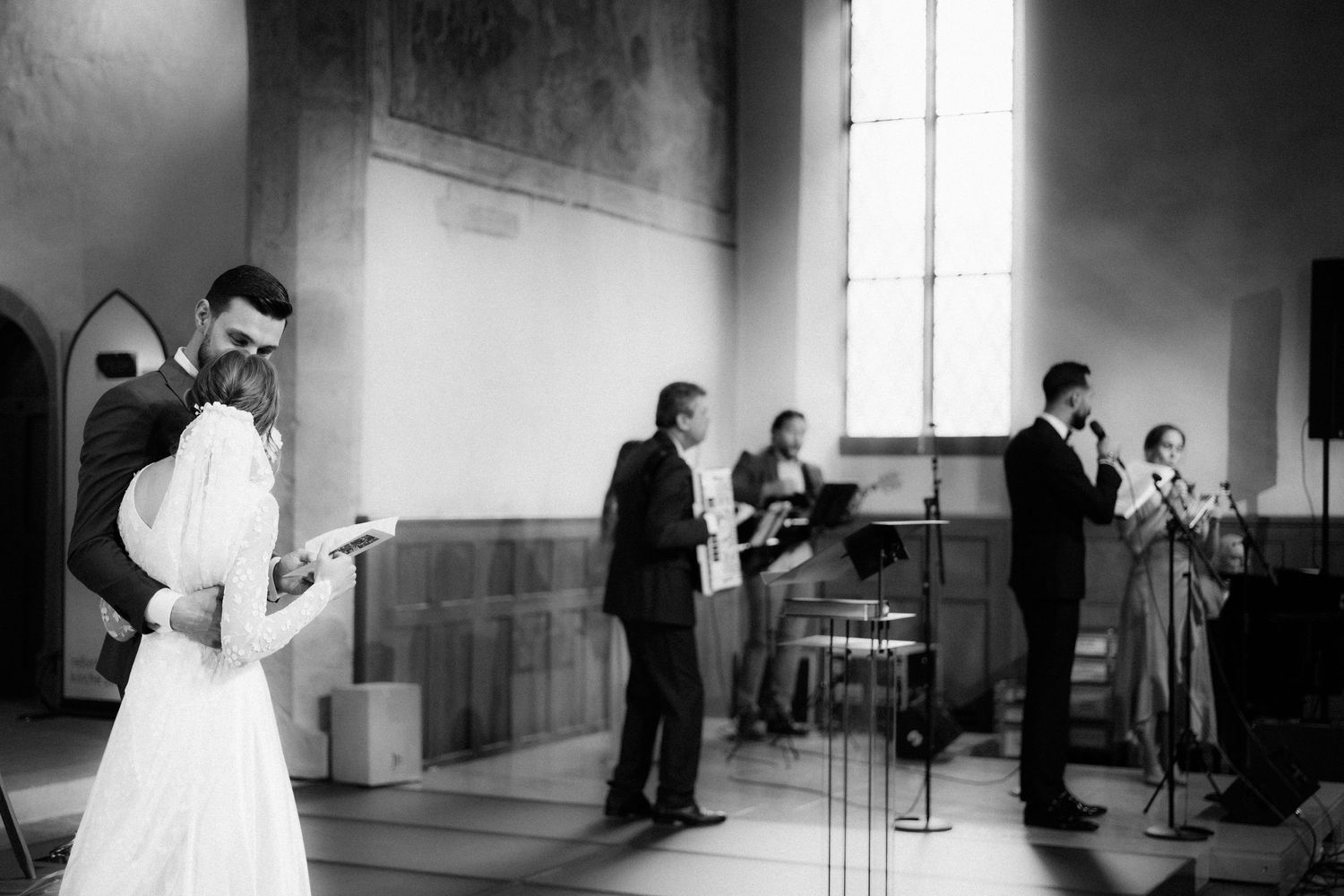 Black and white photo of a wedding party performing music together in a church venue during a ceremony.