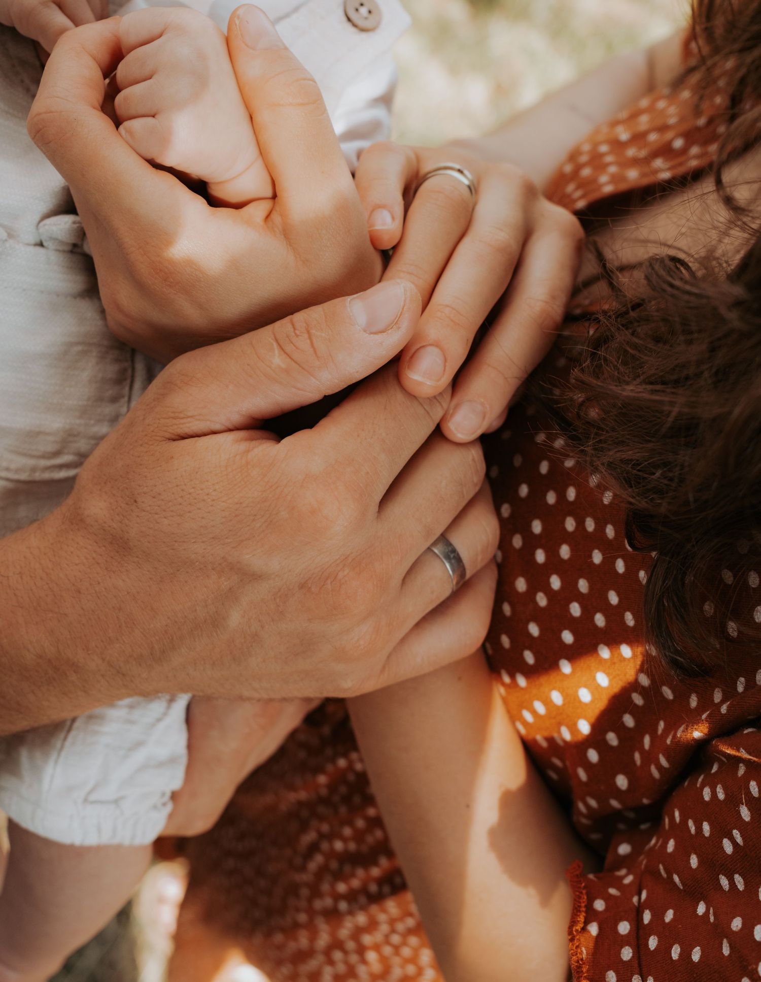Series of hands intertwined against orange polka dot dress fabric.