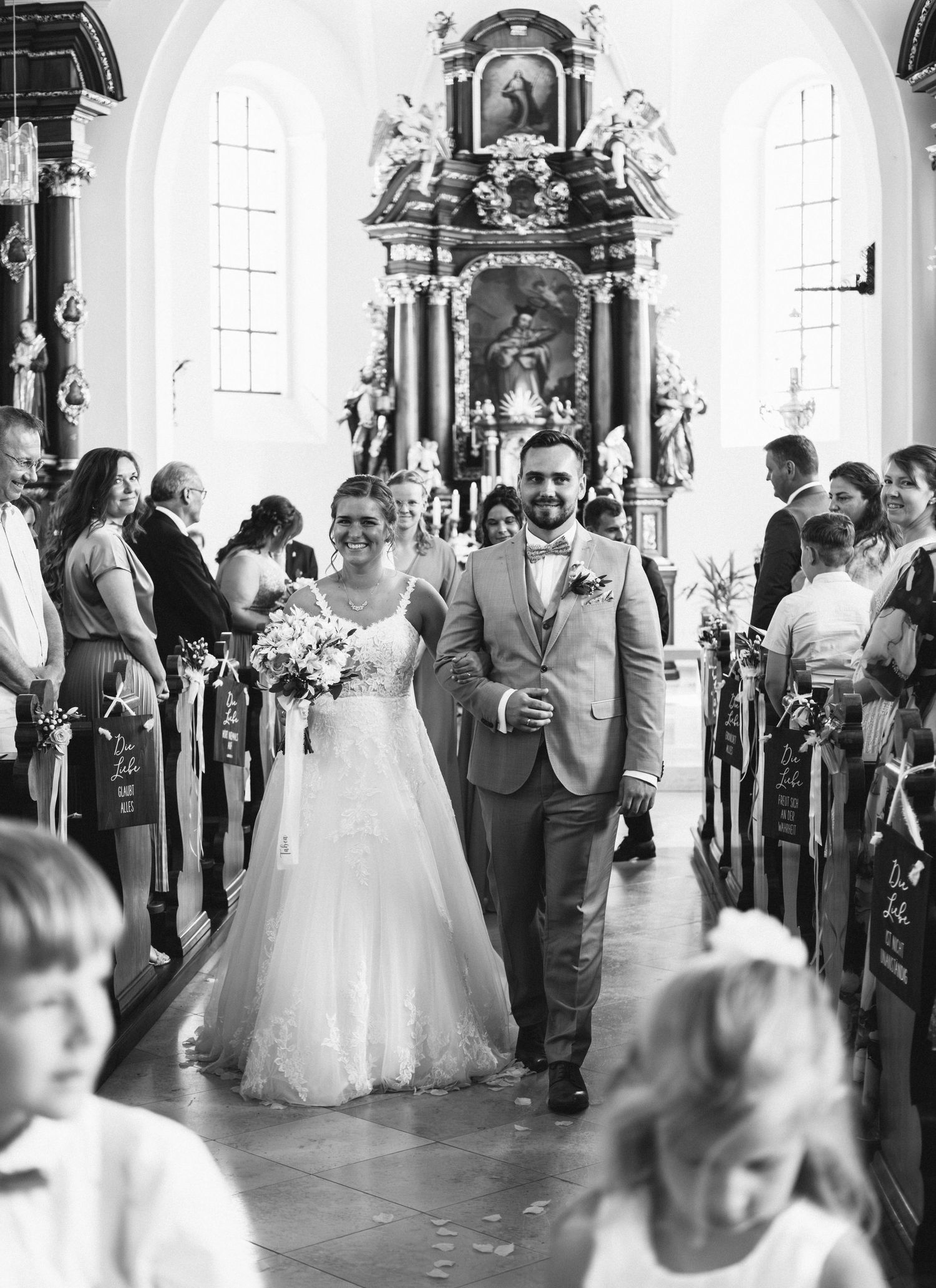 A joyful wedding ceremony in a traditional church with ornate altar decorations and guests lining the pews.