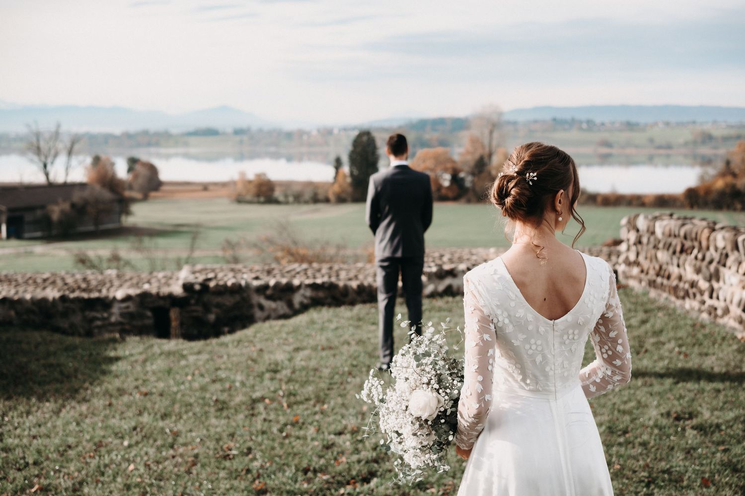 A scenic outdoor wedding ceremony setup with wooden chairs and floral arrangements against a natural landscape backdrop.