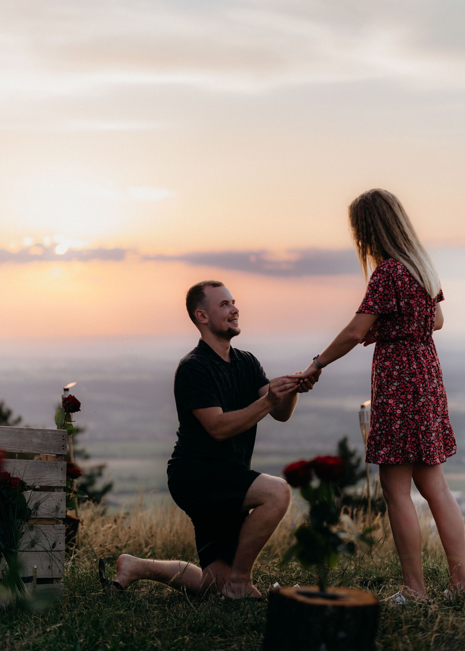 A romantic sunset proposal sequence captured on a hilltop with scenic mountain views in the background.