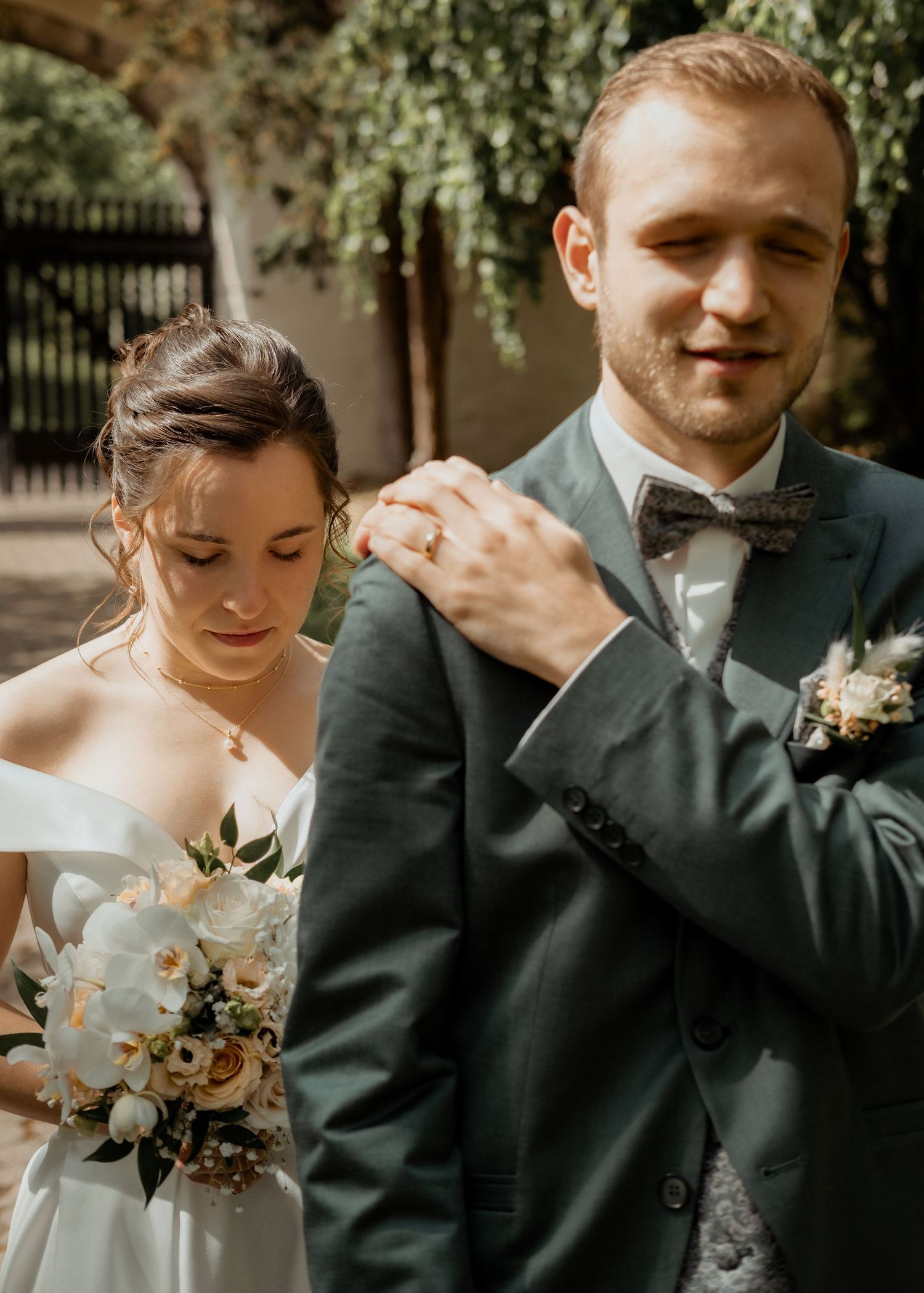 Wedding couple sharing a tender moment outdoors with natural lighting and greenery.