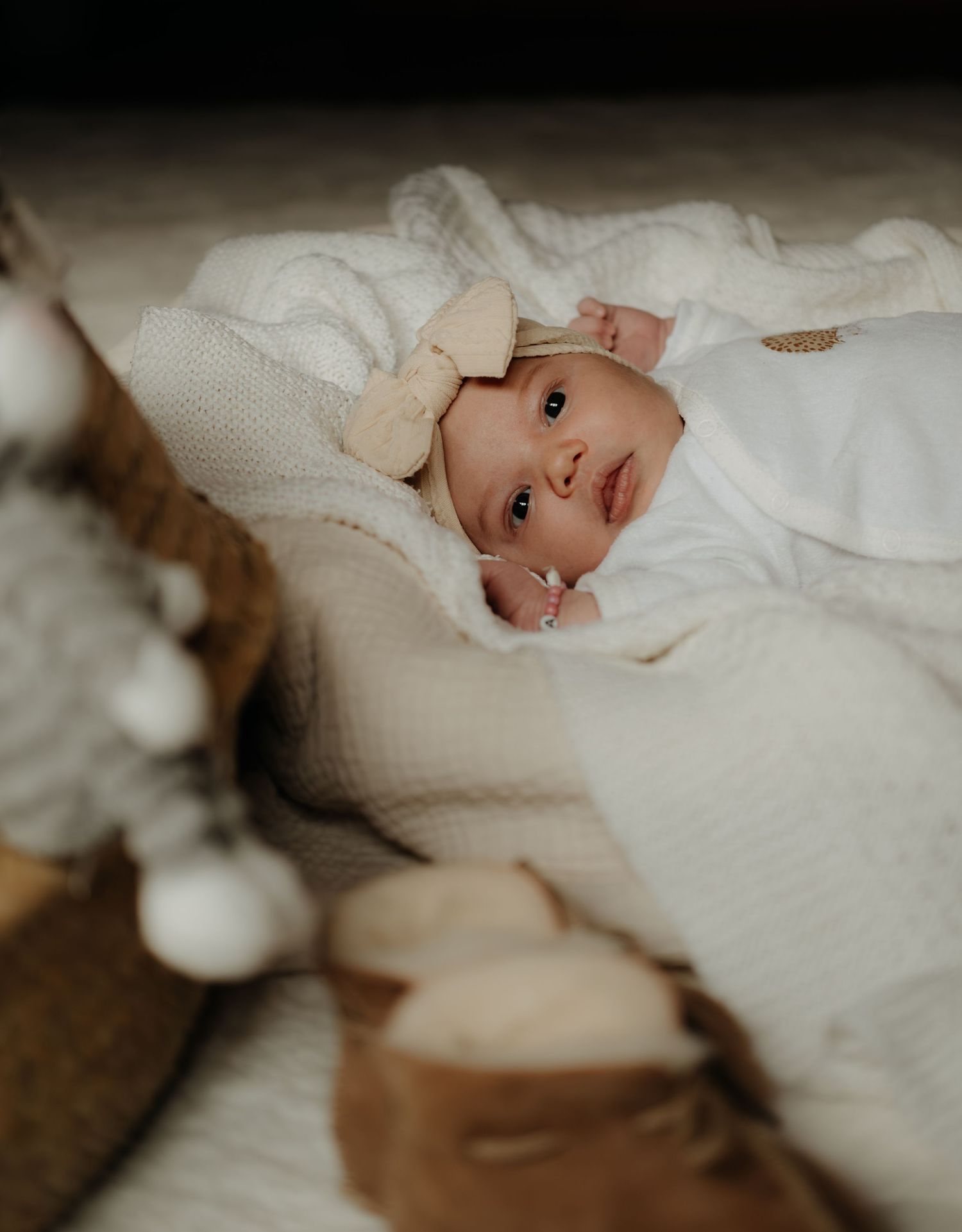 A series of close-up photos showing a baby wearing a white knit sweater while laying on soft bedding.