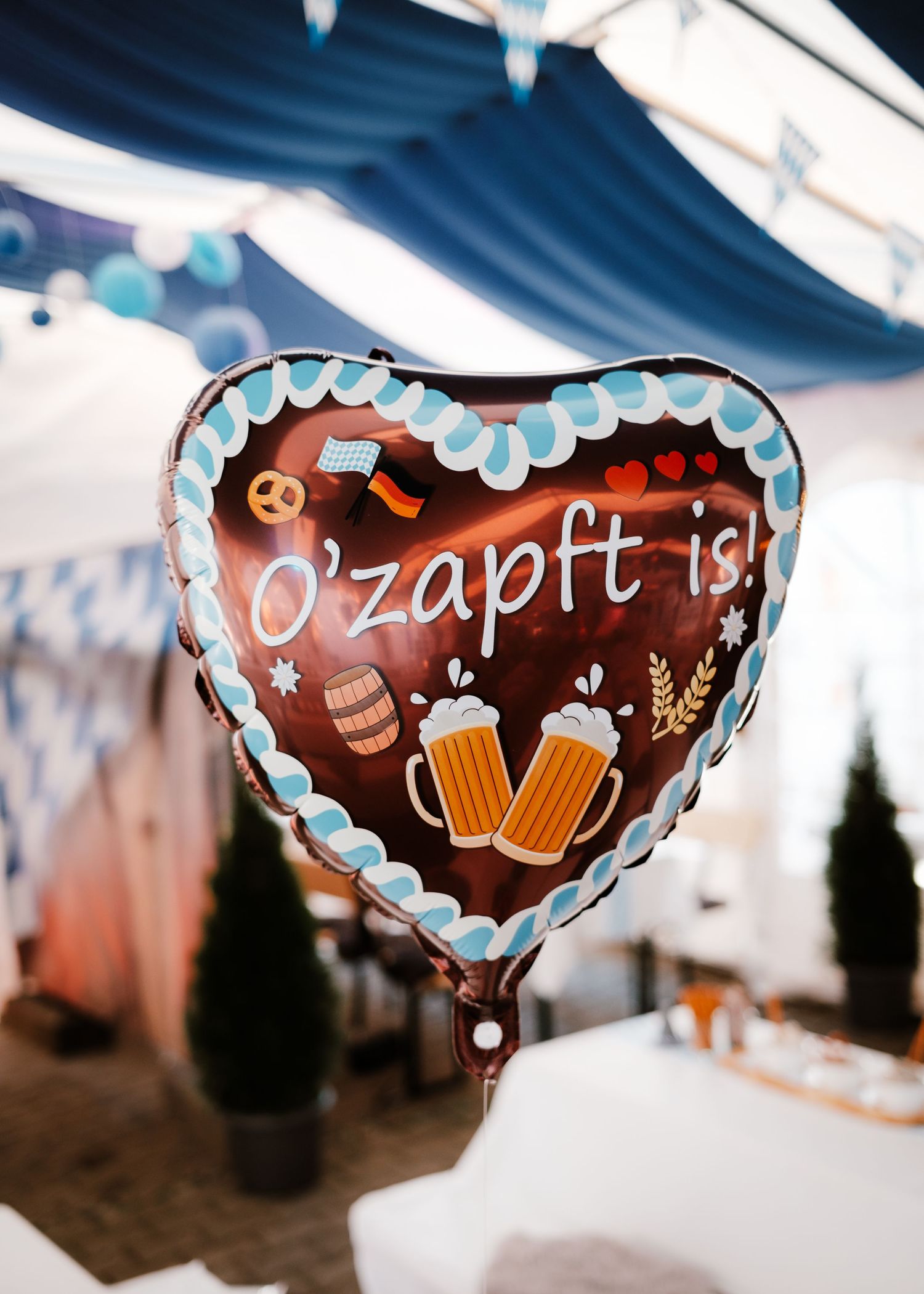 Decorative heart-shaped gingerbread cookies with Oktoberfest-themed designs and beer mug illustrations hang at a festival.