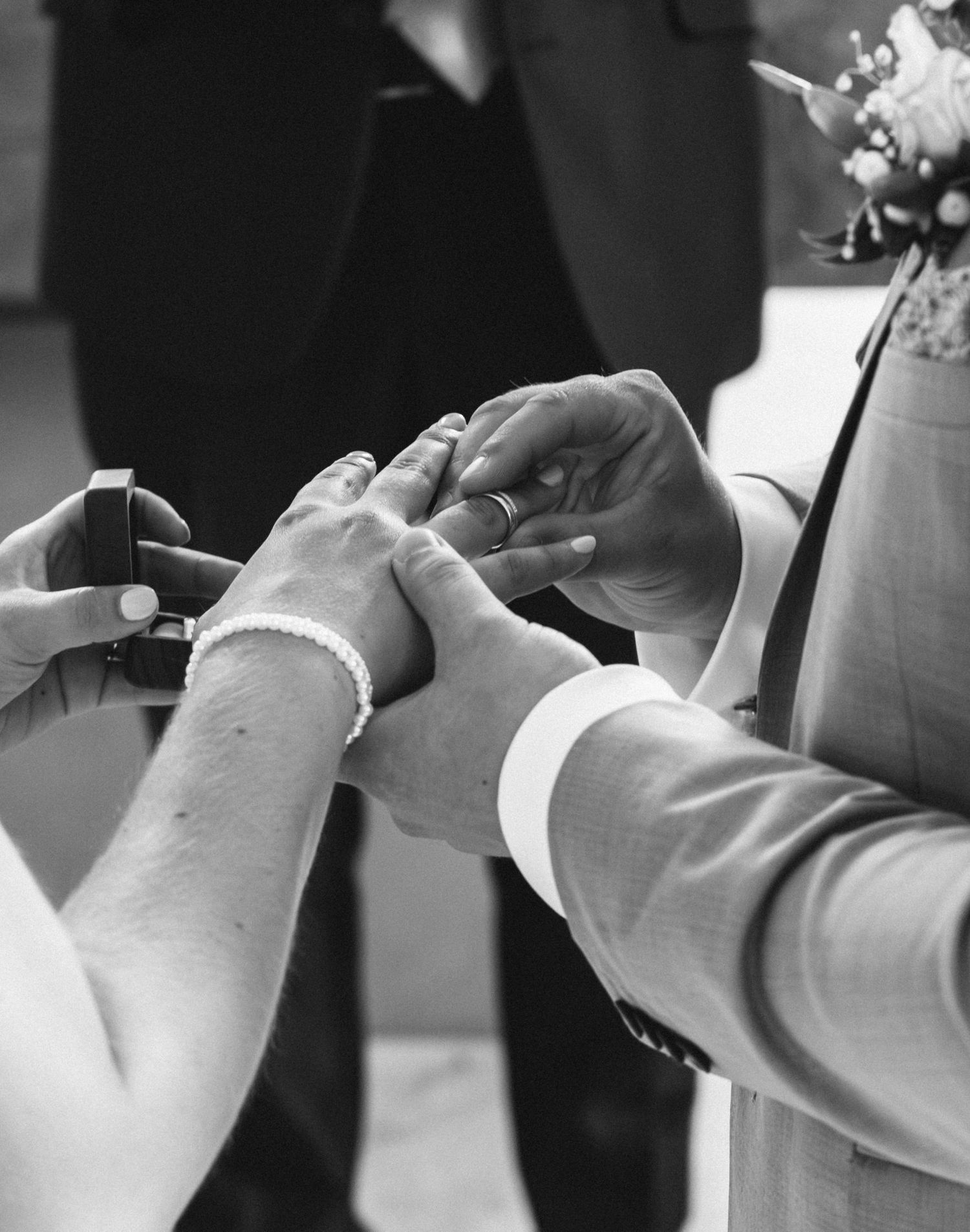 Black and white close-up shots of hands exchanging wedding rings during ceremony.