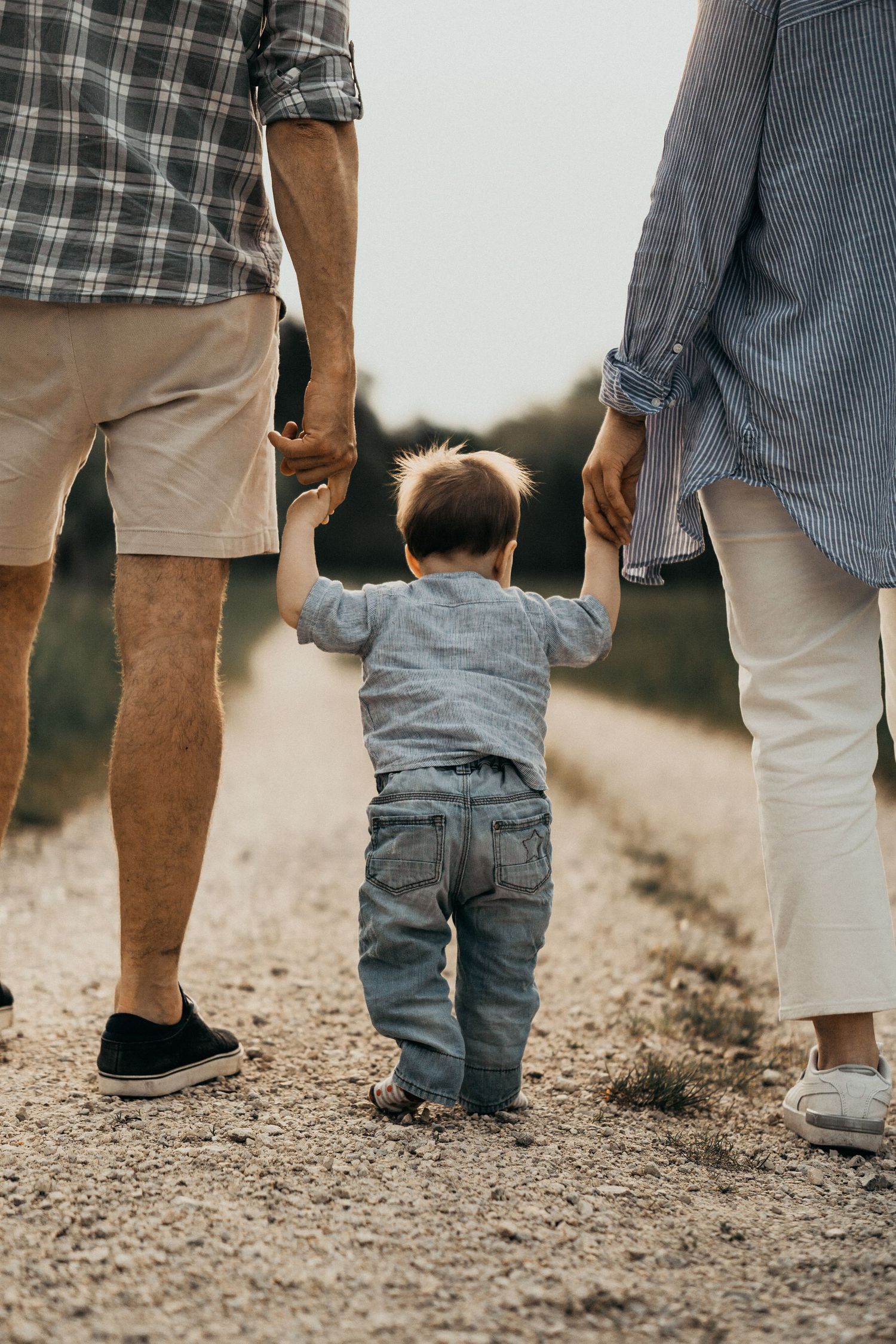 A sequence of photos showing a small child walking between two adults on a dirt path, captured from behind.