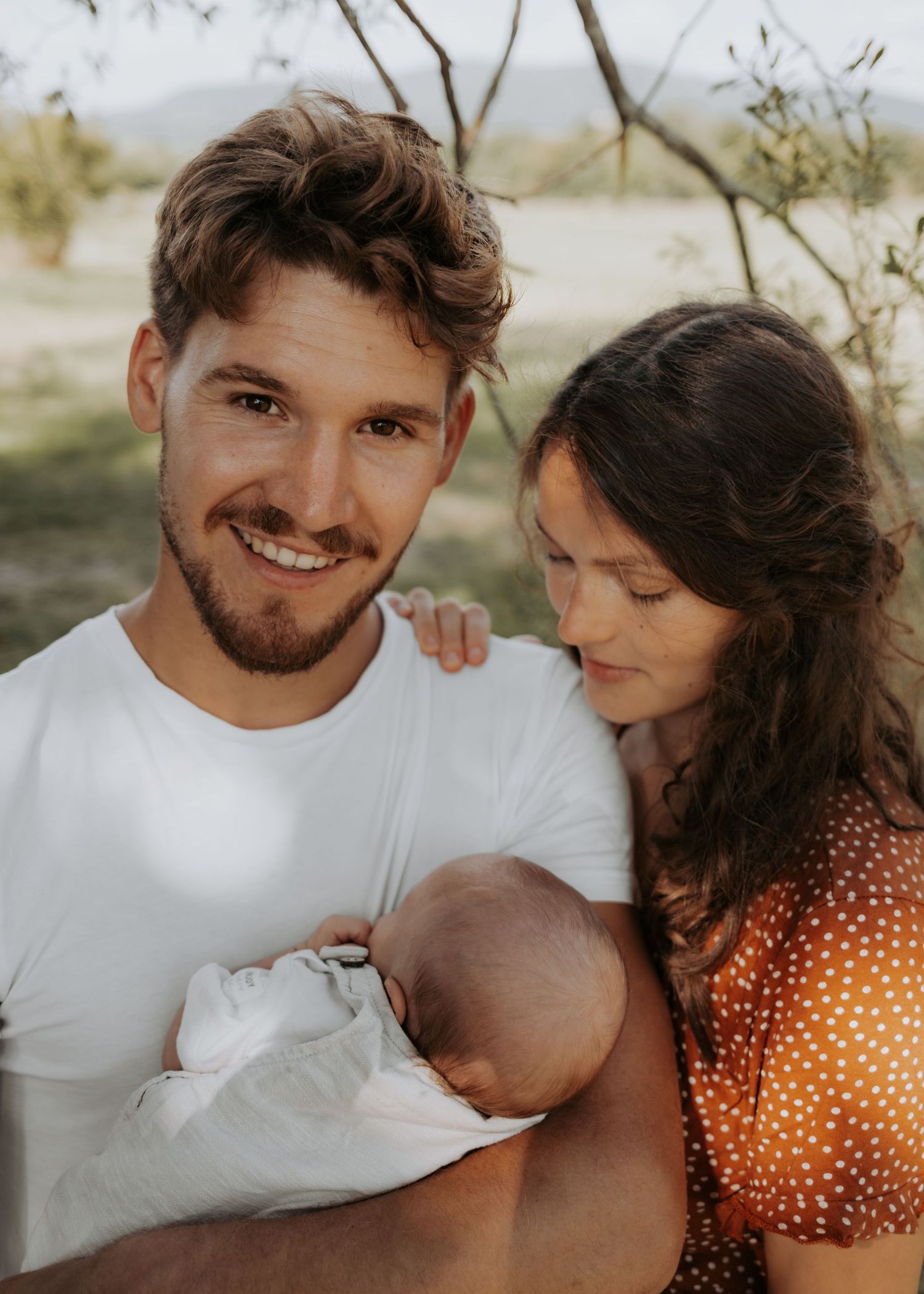Romantic couple in white and polka dot outfits share tender moments in a series of outdoor photos.
