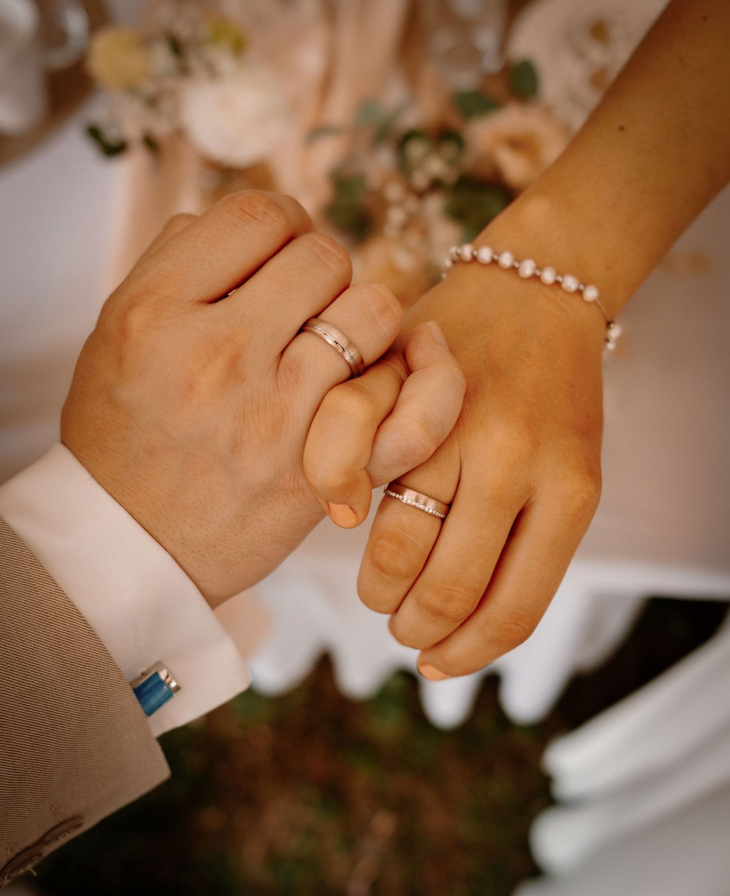 A series of hands showing wedding rings and jewelry in warm lighting during a wedding celebration.