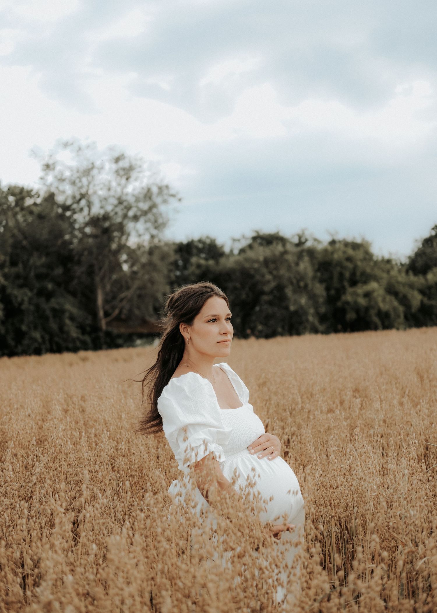 A series of photos showing someone in a white dress standing in a golden wheat field under cloudy skies.