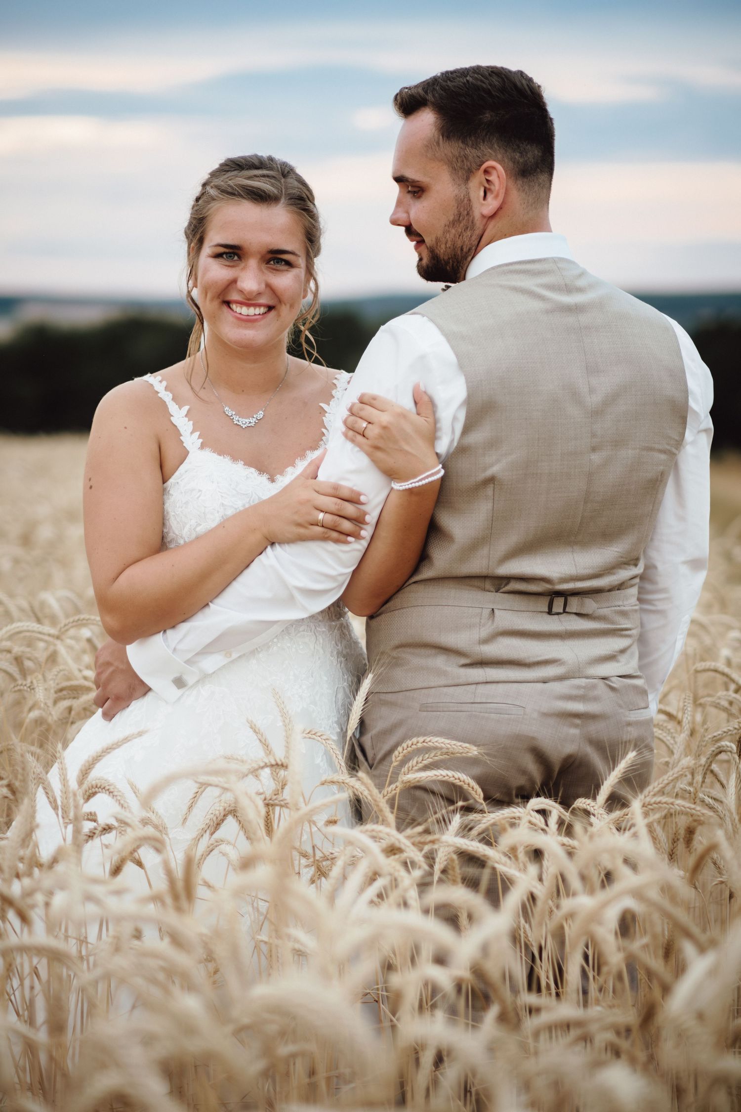 A couple shares intimate moments while sitting together in a golden wheat field during sunset.