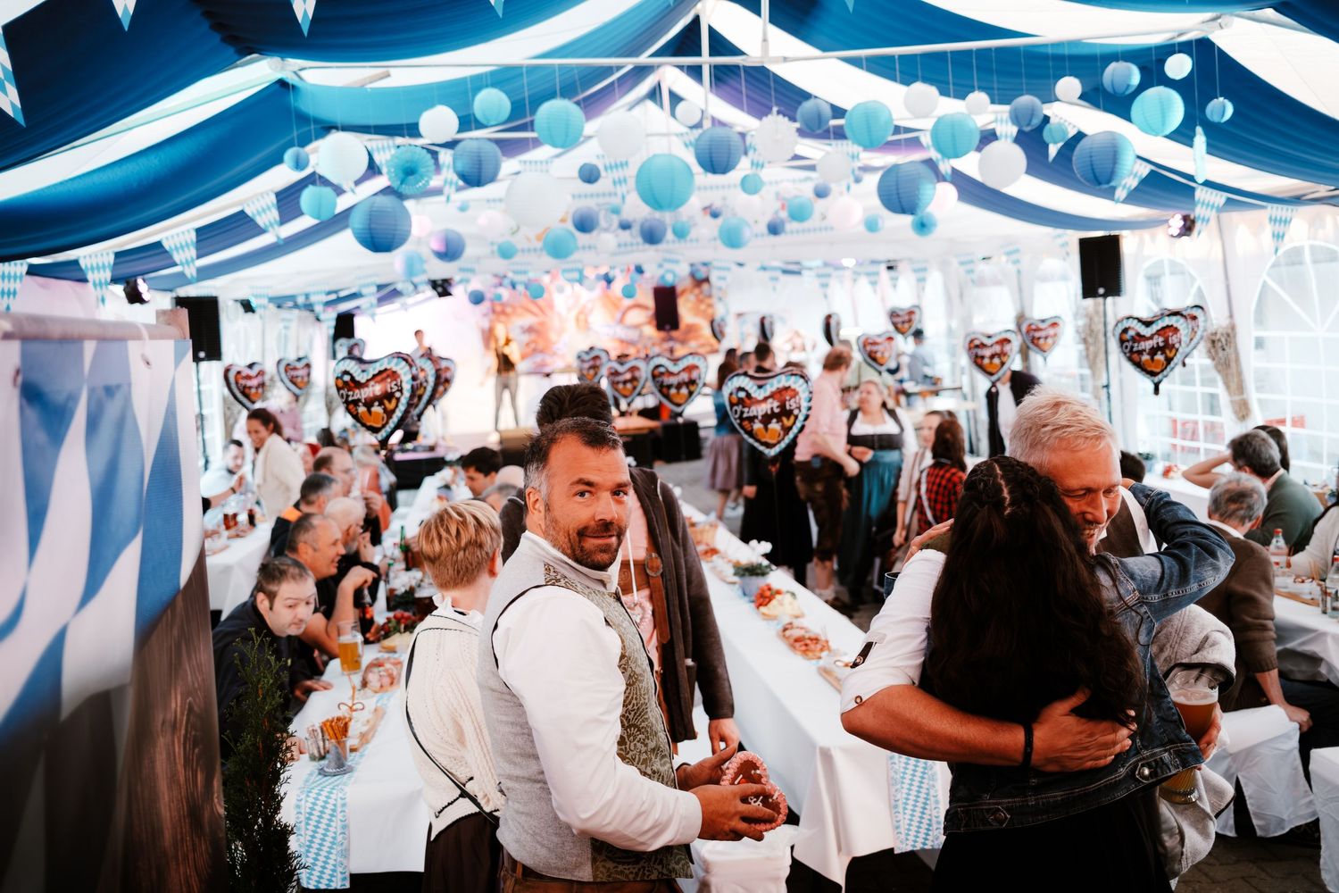 Wedding guests dancing and celebrating under elegant blue and white draped ceiling decorations at a reception party.