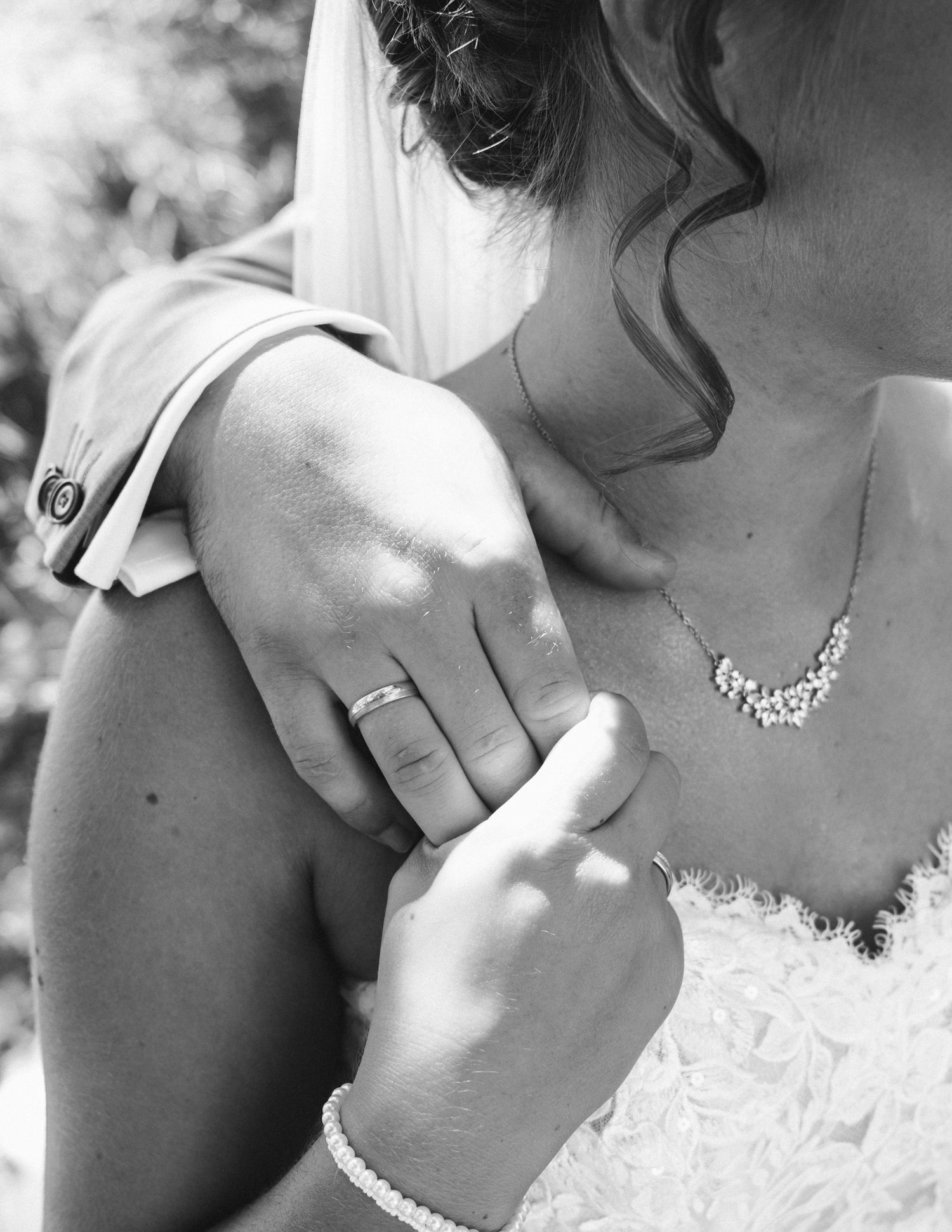Black and white close-up of a bride's neckline showing delicate lace details and jewelry.