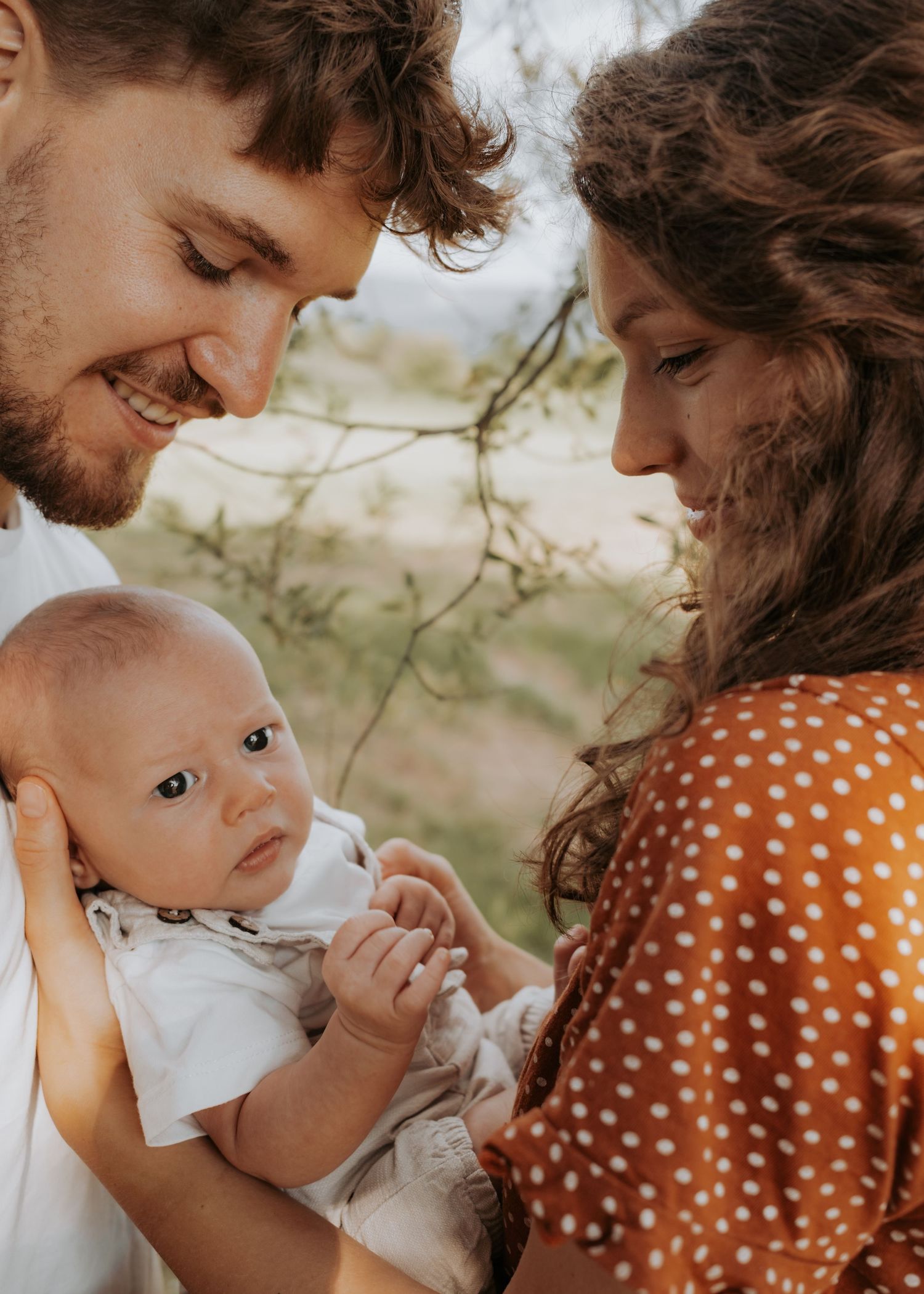 Outdoor family photoshoot sequence featuring intimate moments in polka dot dress and white shirt.