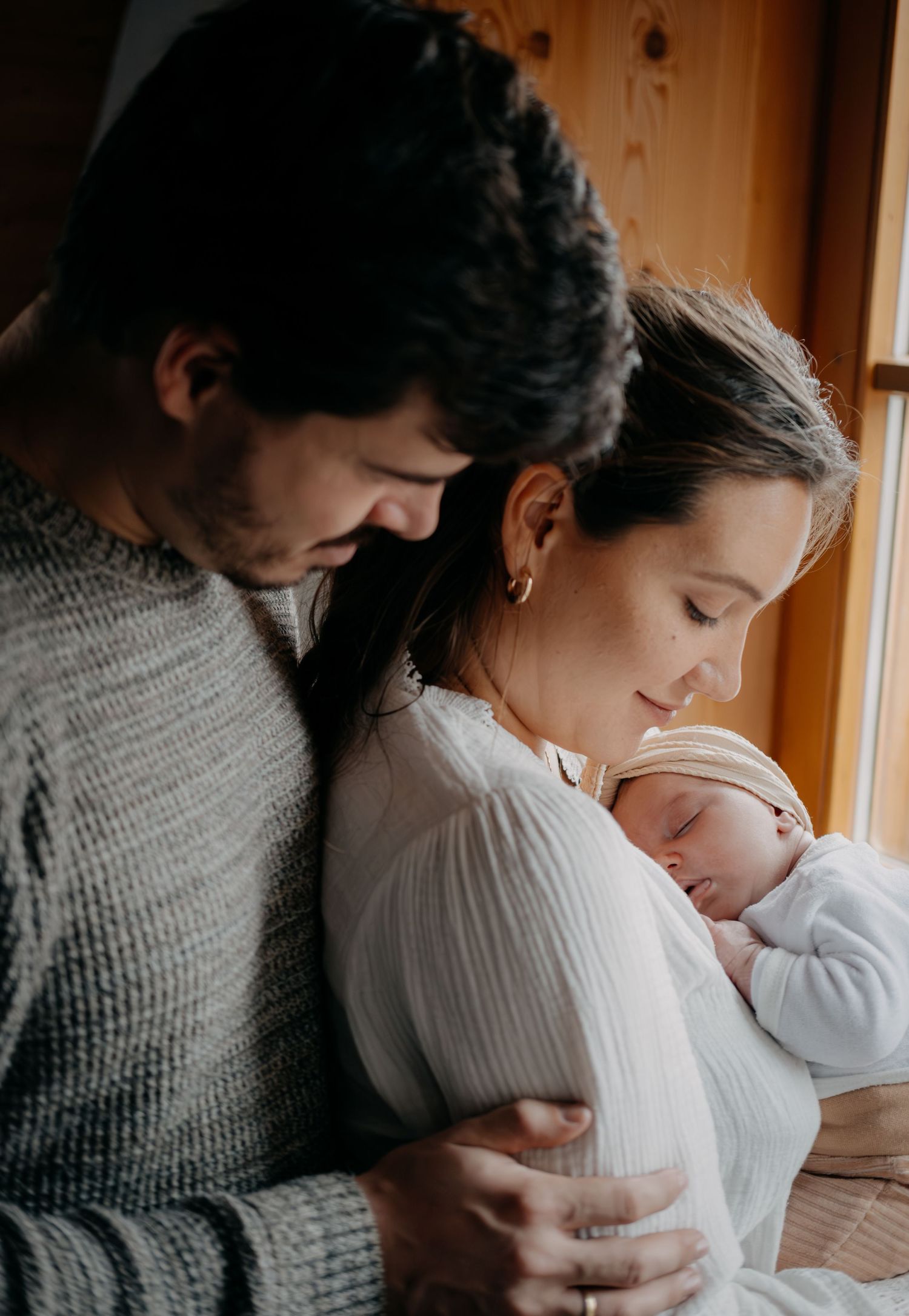A tender series of intimate family moments showing parents cradling and kissing their newborn baby in warm natural light.