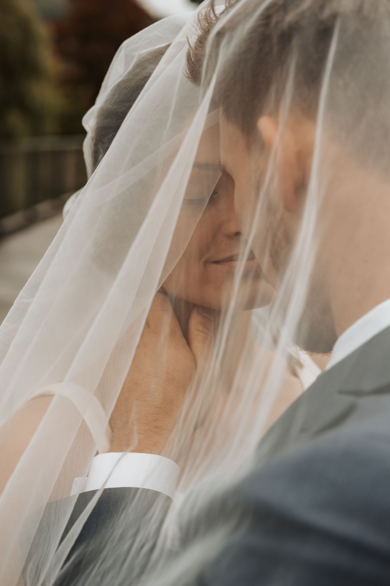 Close-up view of a bride in white veil standing next to groom during wedding ceremony.