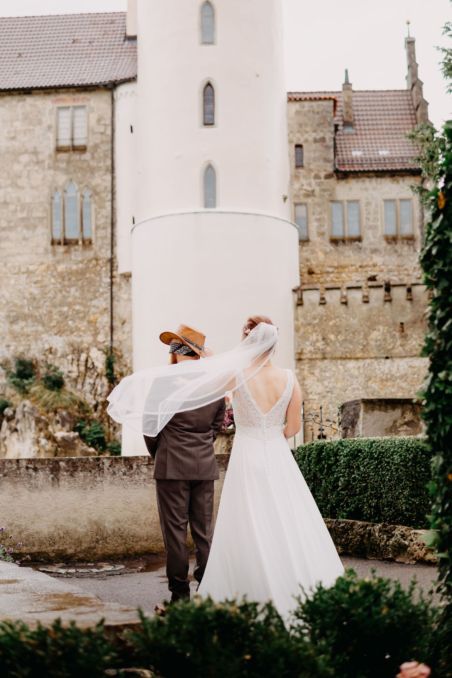 Wedding couple dances together on the grounds of an old stone castle with beautiful architectural details.