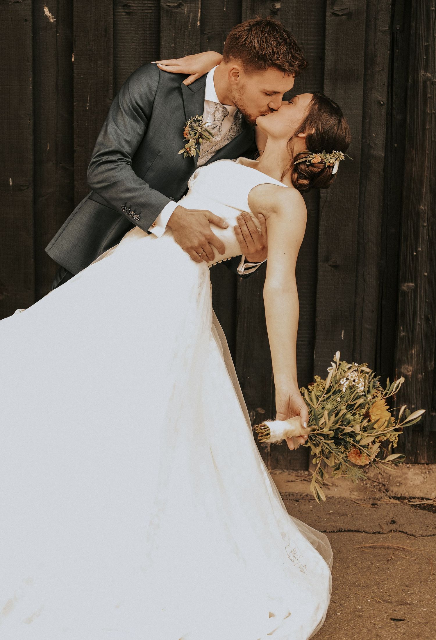 A romantic wedding couple shares a passionate kiss while the groom dips the bride in her flowing white gown.