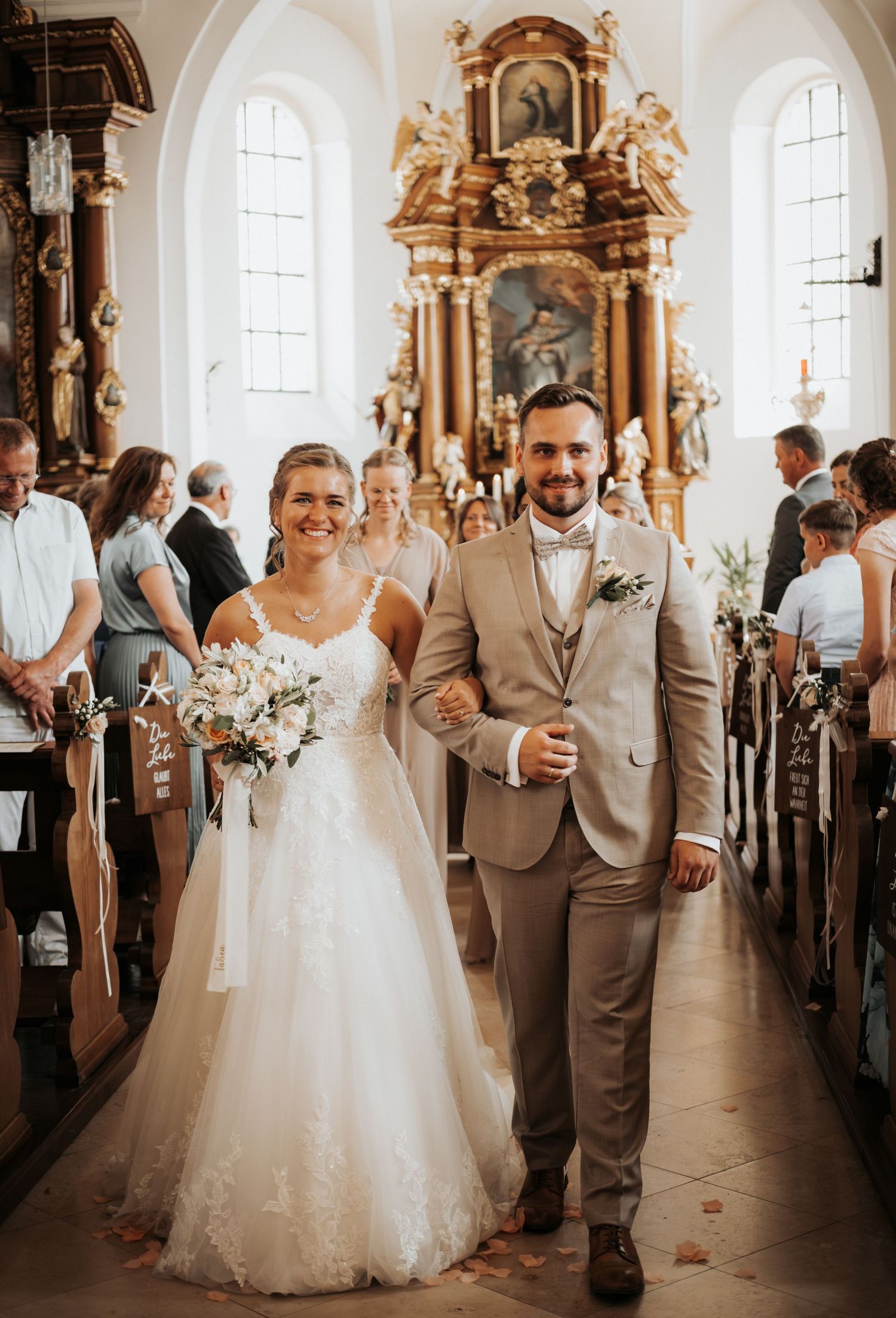 Elegant church wedding ceremony with guests seated in wooden pews.