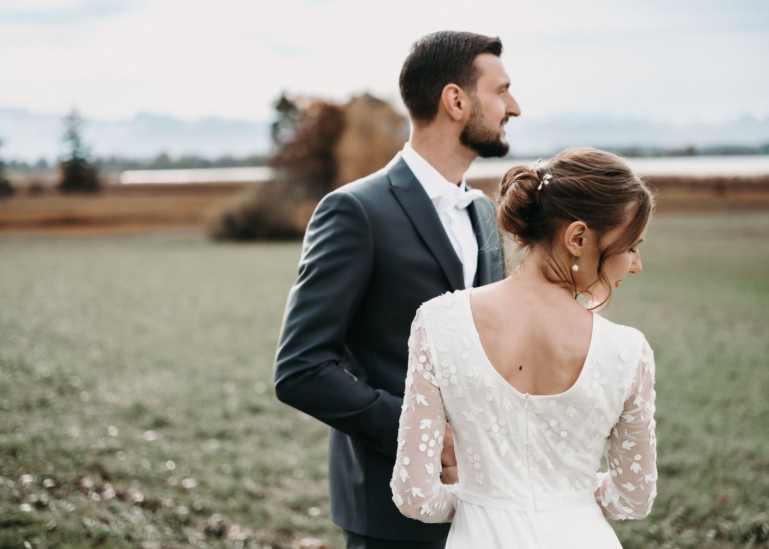 A bride and groom share an intimate moment in a rustic outdoor field setting during their wedding photoshoot.