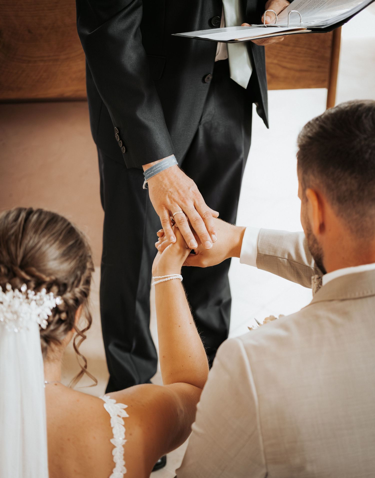 A bride in a white dress helps the groom adjust his bowtie in a series of intimate wedding preparation photos.