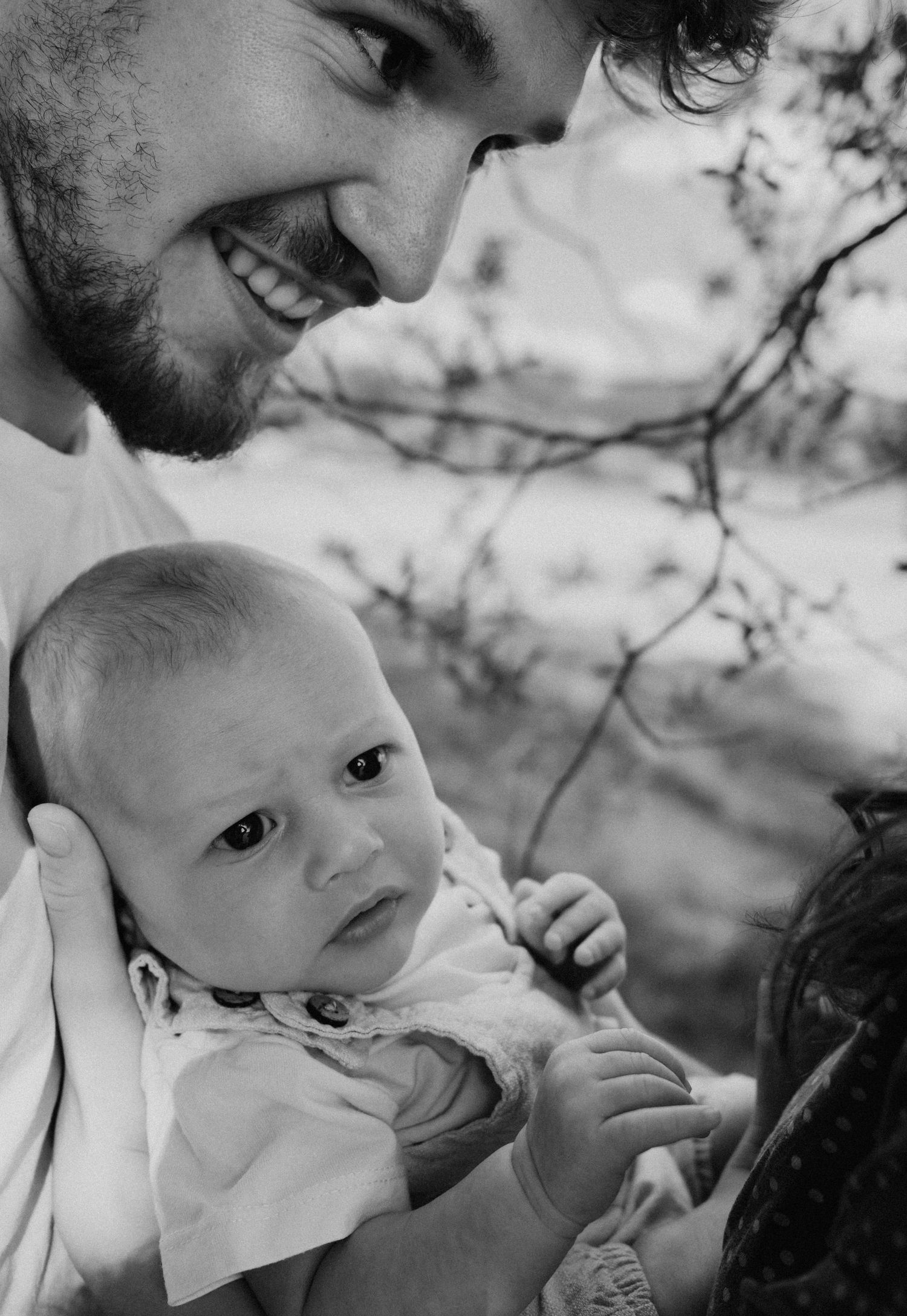 Intimate black and white portrait series showing tender moments between parents and their infant.