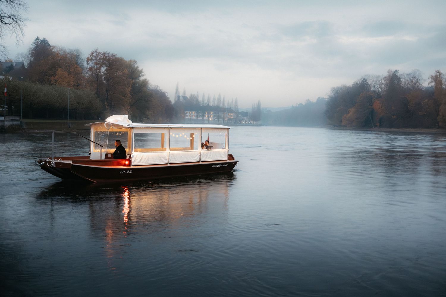 A small wooden houseboat floats peacefully on a misty lake during a foggy morning.