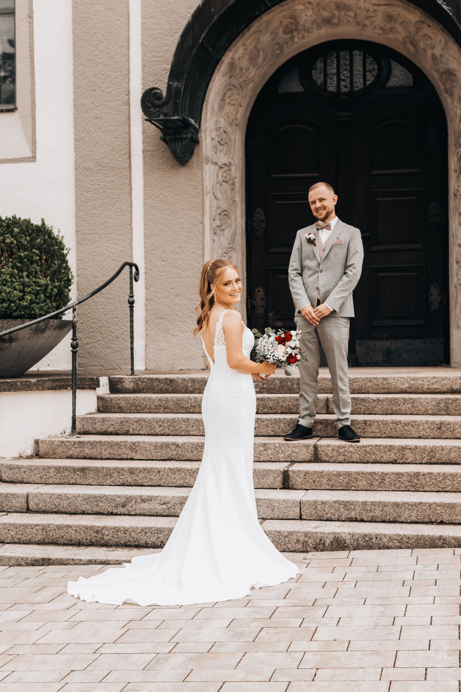 A wedding first look moment captured in a series of photos on stone steps outside an elegant church entrance.