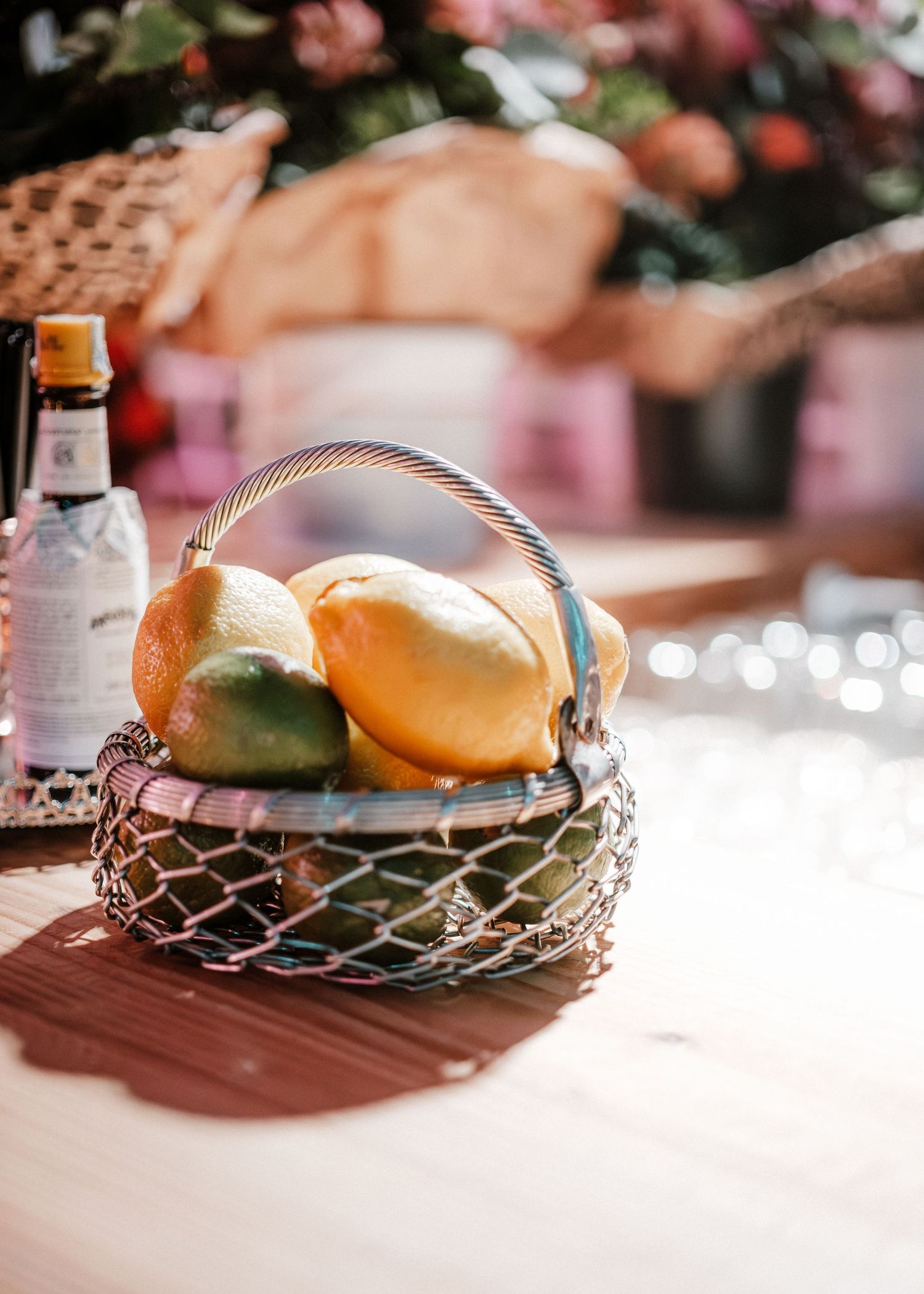 Fresh tropical fruits arranged in a decorative metal wire basket on a white surface with soft natural lighting.