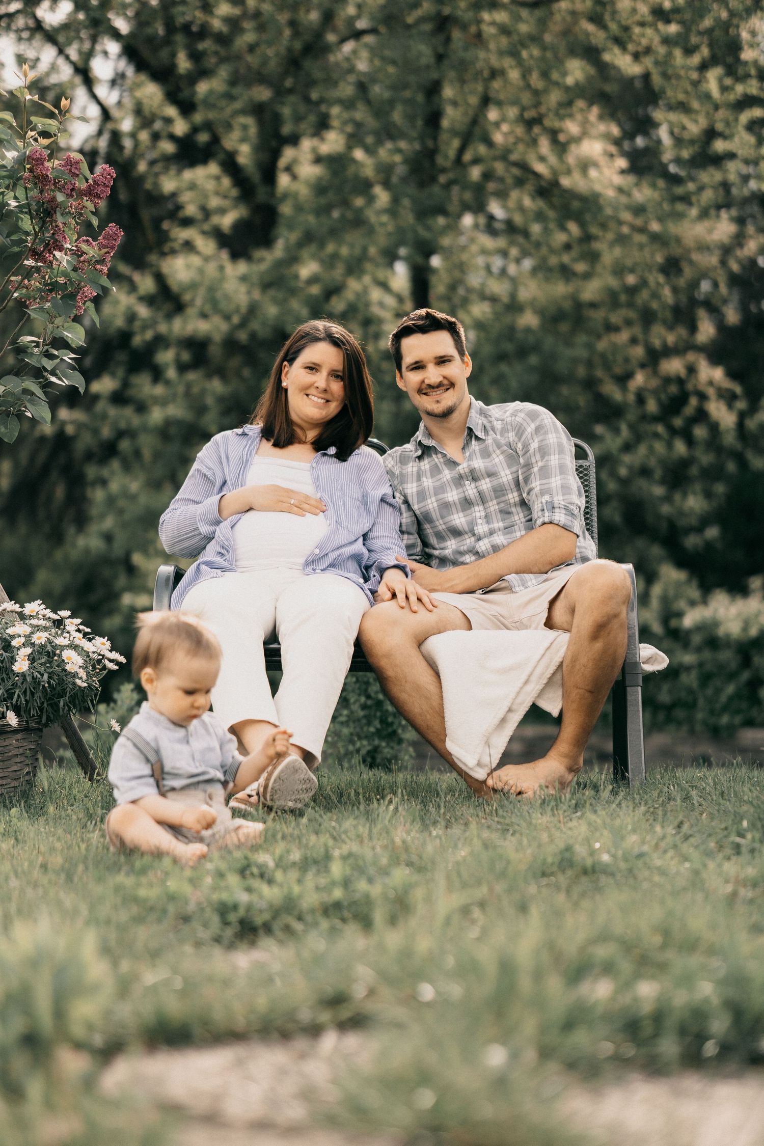 Family relaxing together on grassy hill in park during summer photoshoot.
