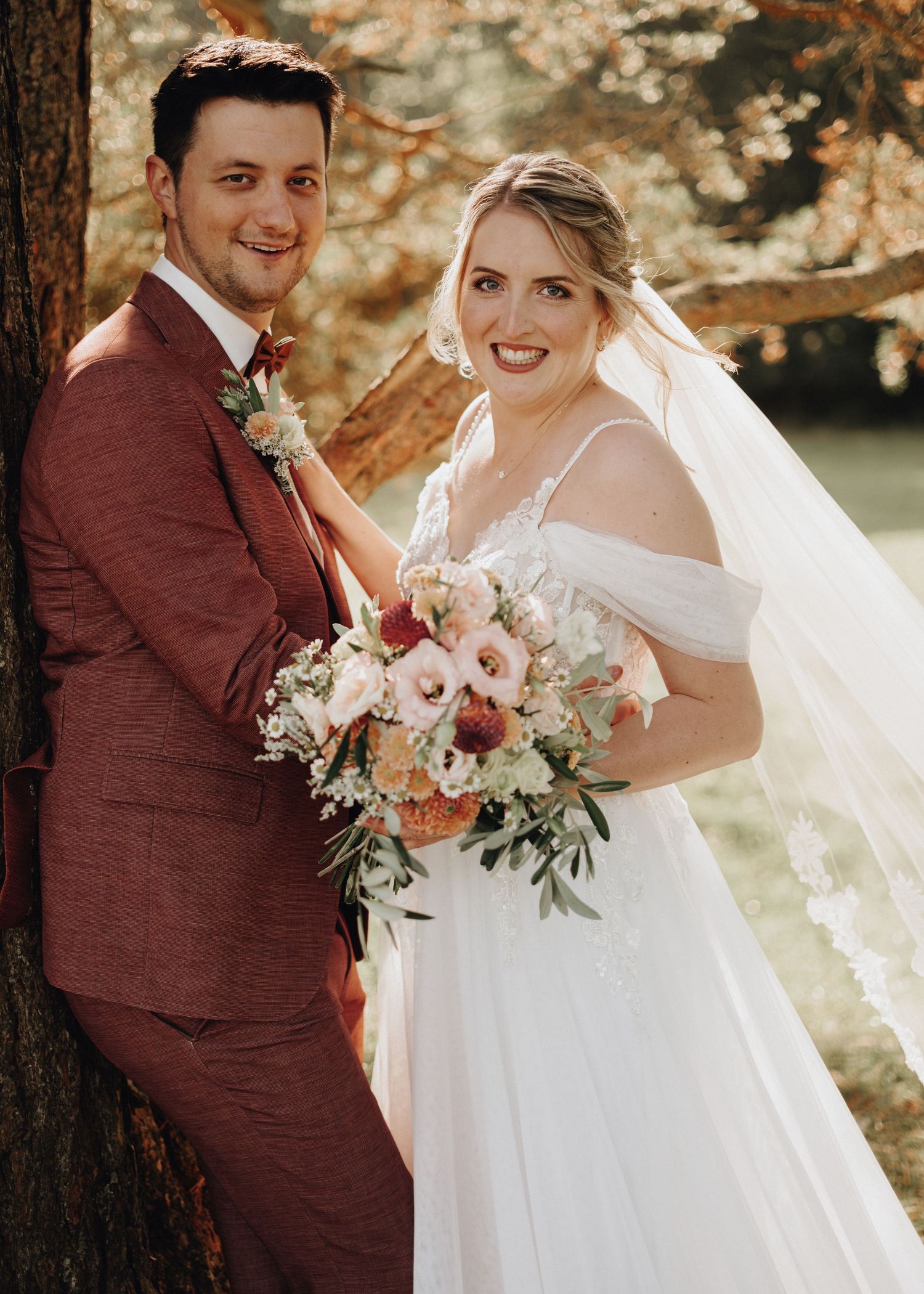 A romantic wedding photoshoot in a forest setting with burgundy and white color scheme and natural lighting.