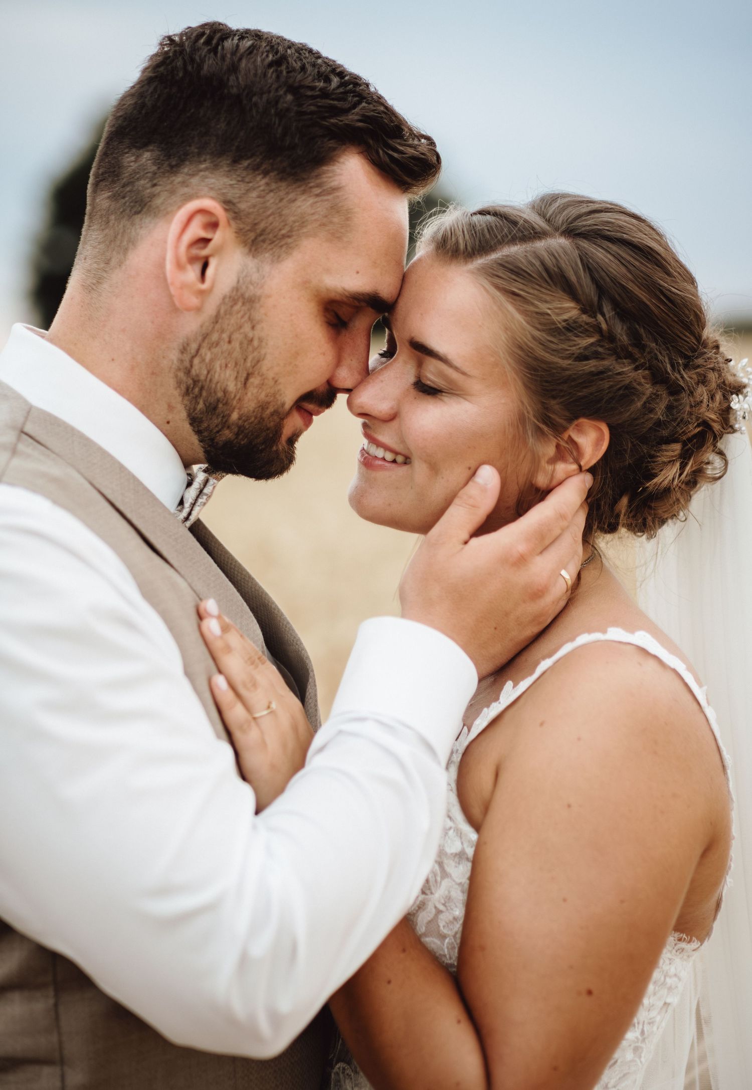 A romantic close-up series of a couple in wedding attire sharing intimate moments and kisses against a light background.