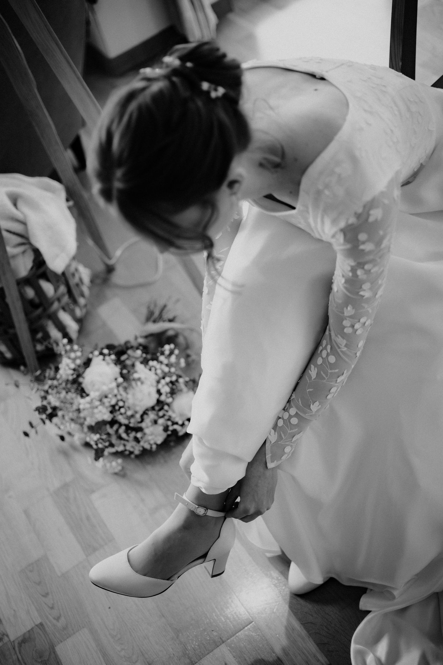Close-up details of a bride's white lace wedding dress and shoes during preparation for the ceremony.