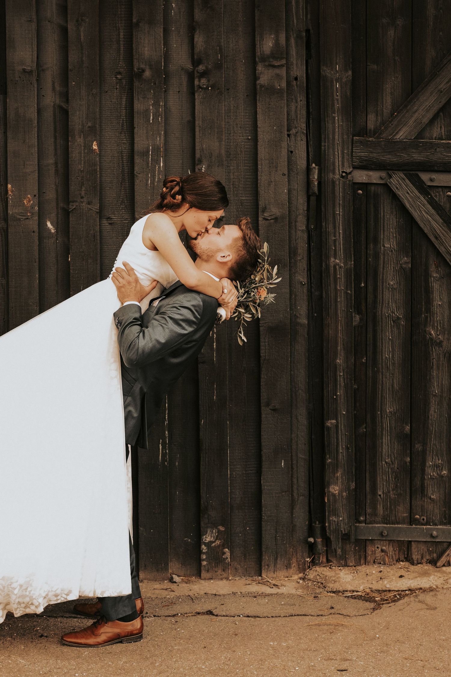 Romantic couple sharing a passionate kiss against a rustic wooden barn wall in a series of four similar poses.