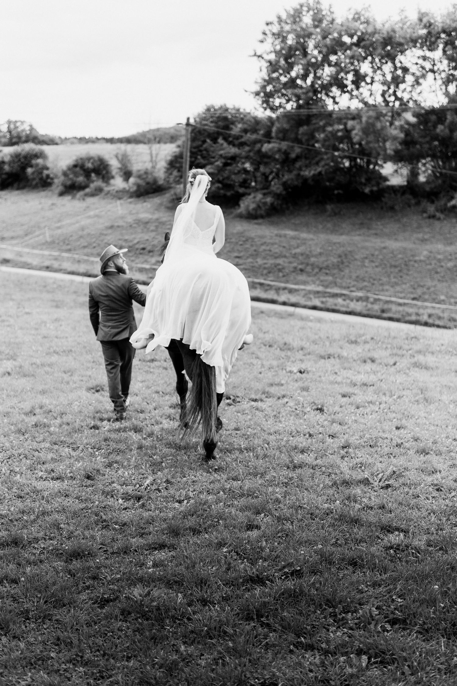 A person in a ghost costume chases a small child across a grassy field in black and white.