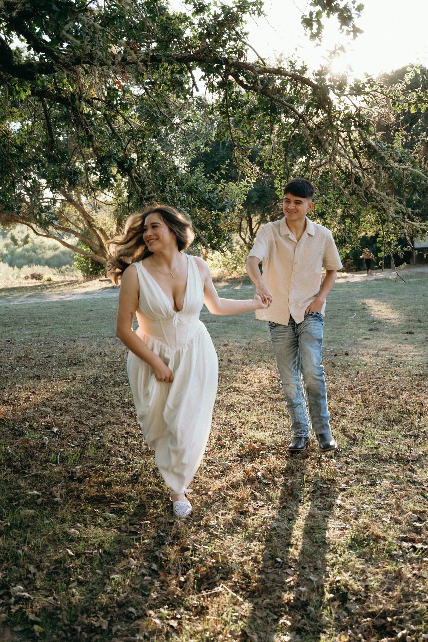 Couple in white and denim playing and laughing together in a natural outdoor setting.