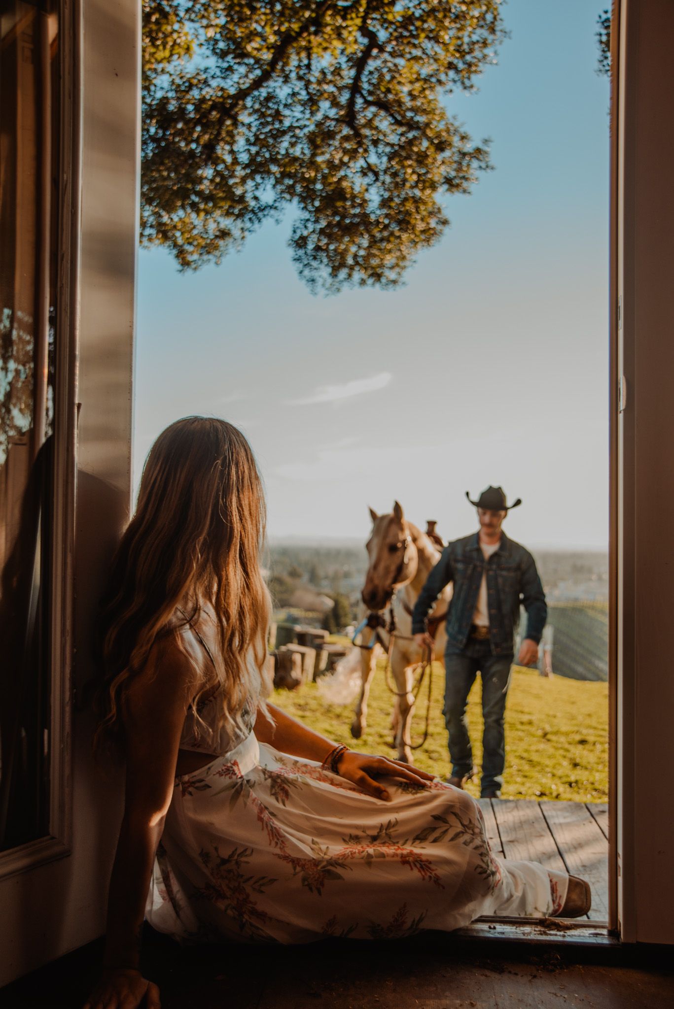 A scenic window view of horses and rolling hills during golden hour.
