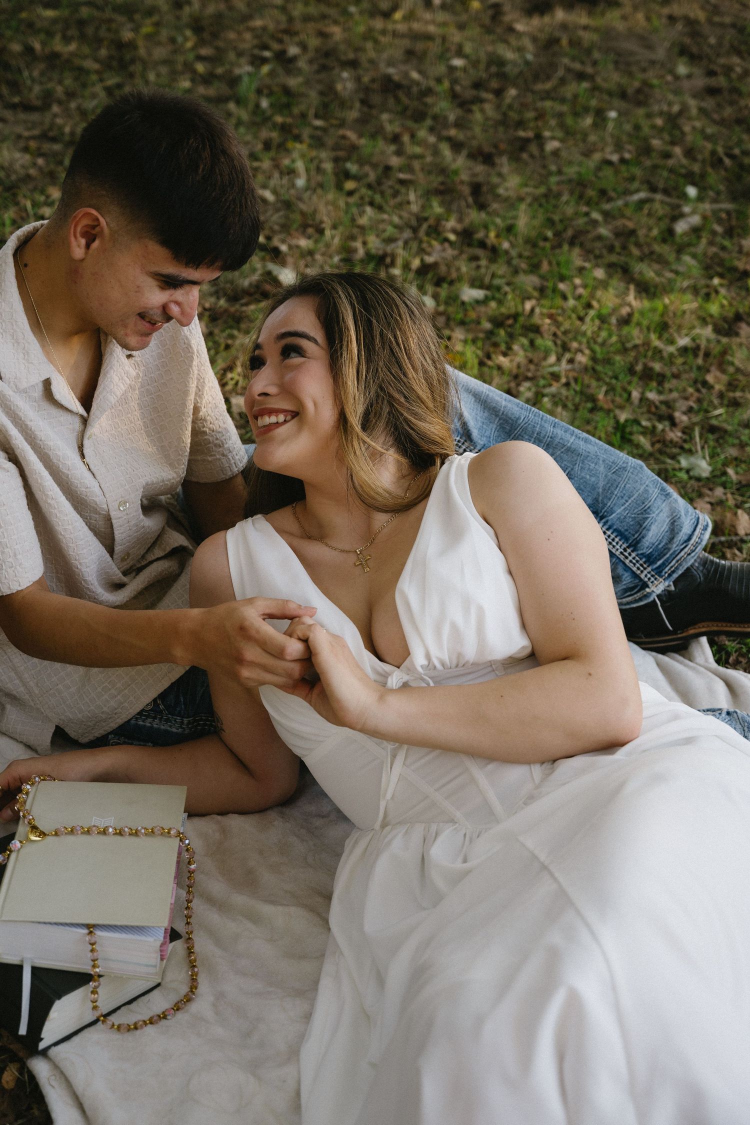 Intimate couple's photoshoot with romantic poses on white blanket outdoors.