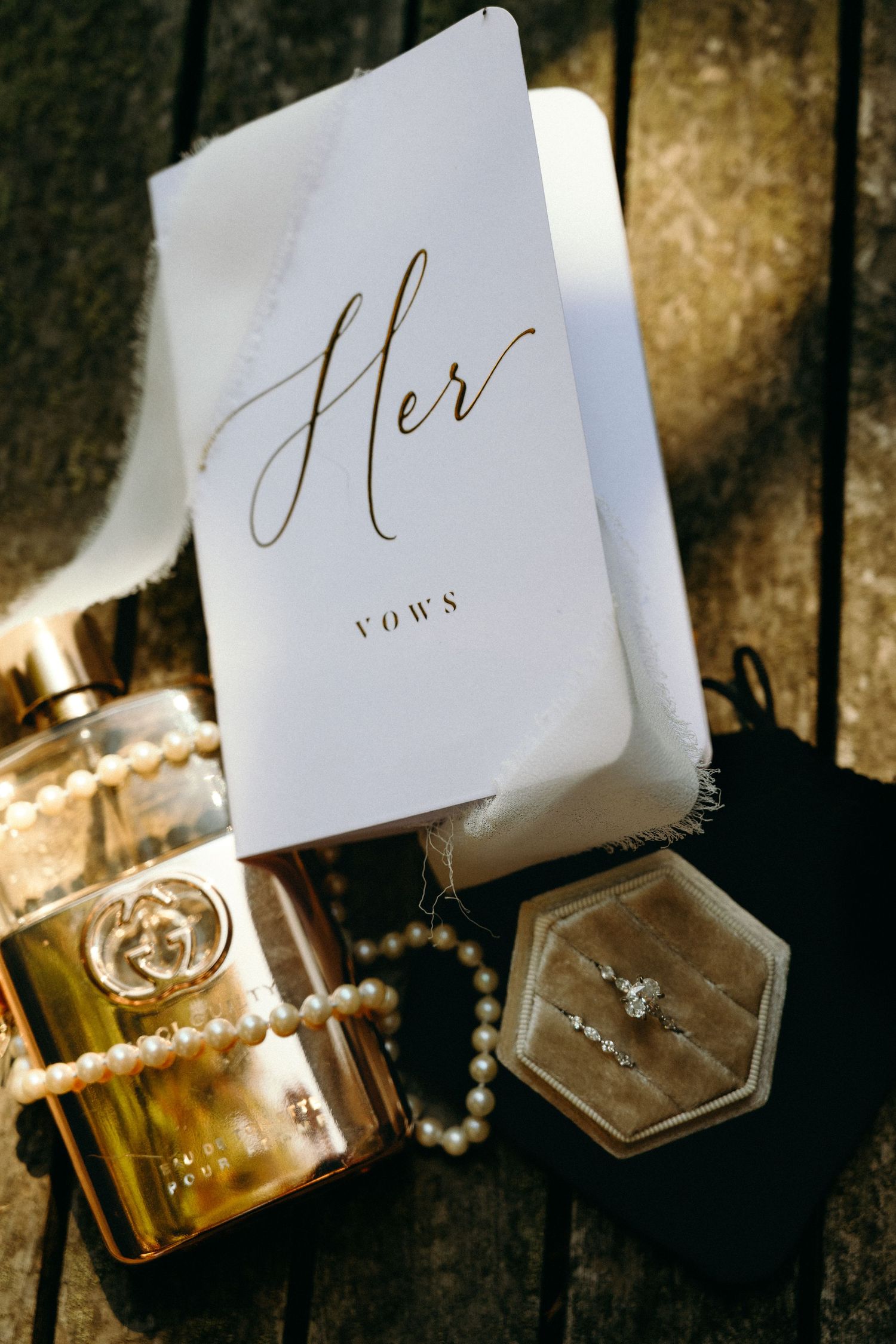 Wedding vow book and perfume bottles arranged in golden sunlight.