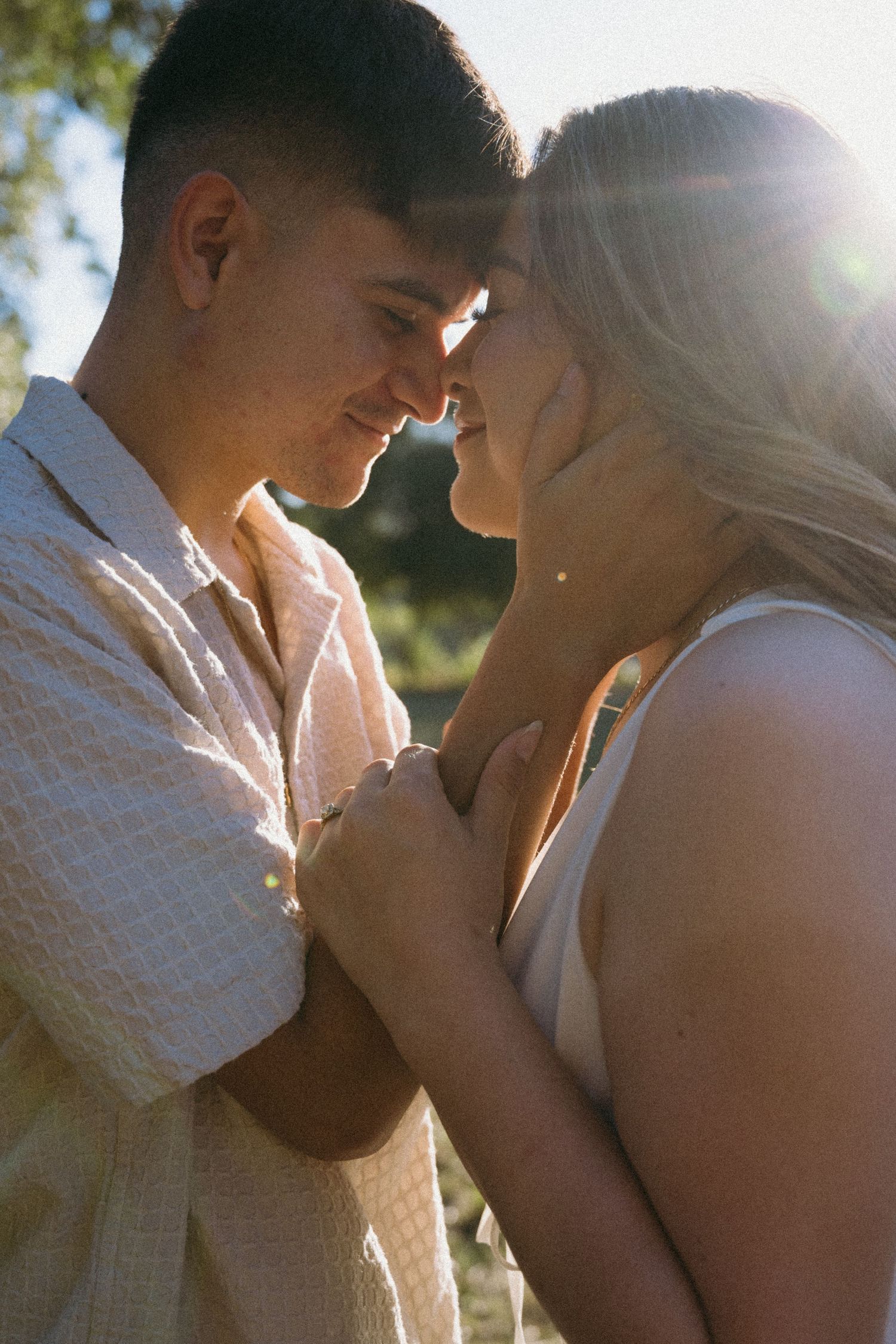 Romantic couple embracing in golden sunlight during an outdoor photo session.