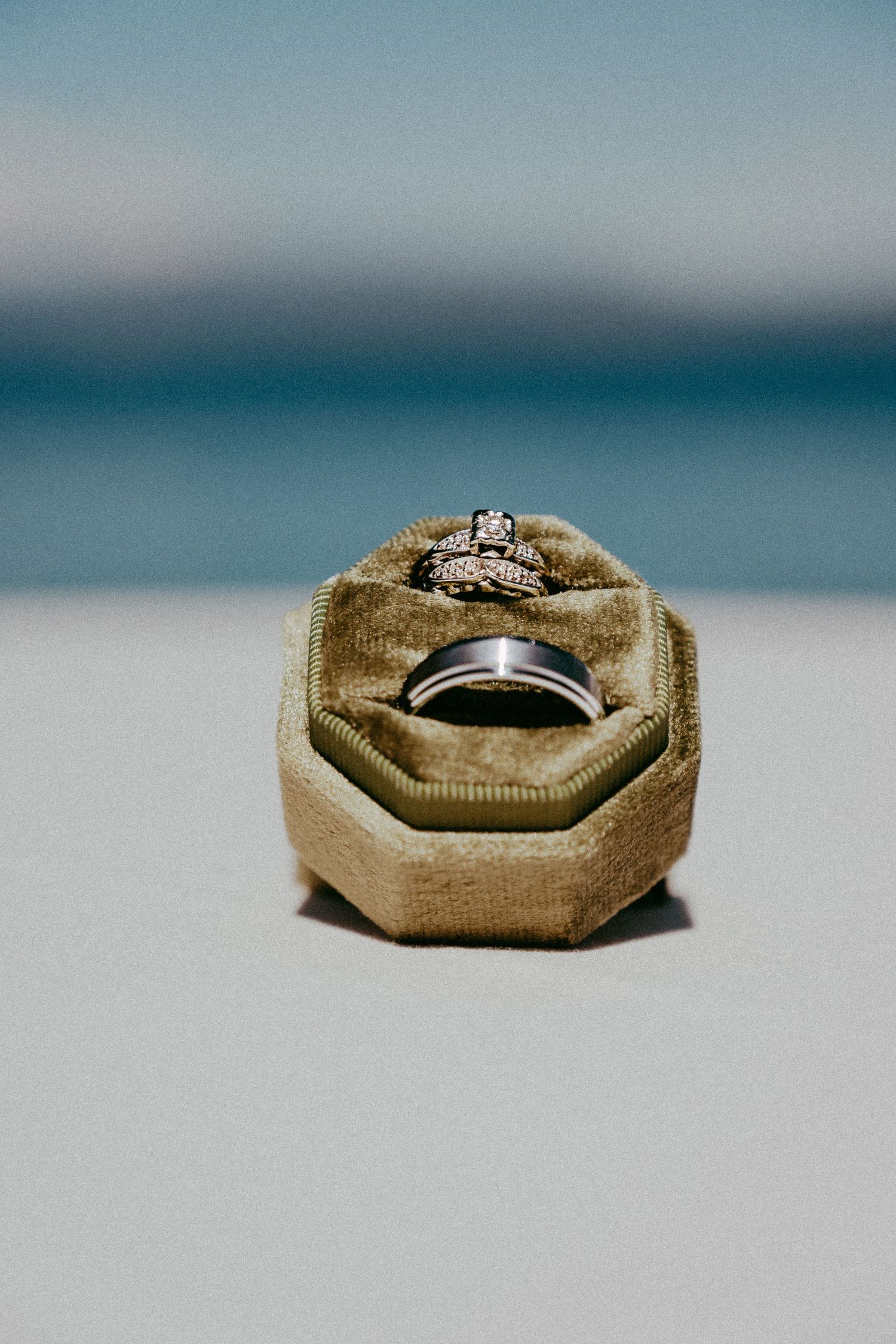 Diamond engagement ring displayed in tan velvet ring box on light surface.
