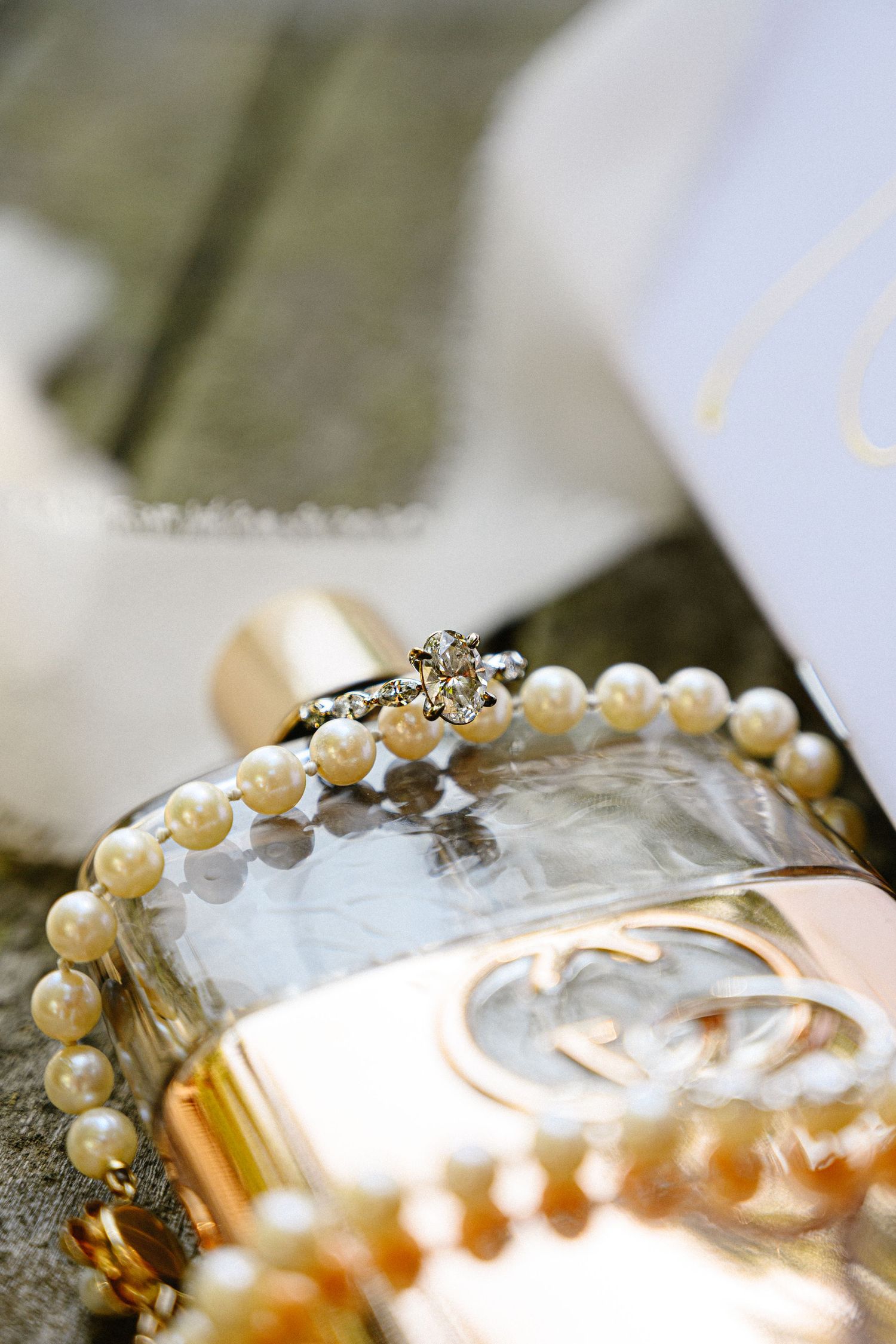 Close-up of pearl details and wedding accessories on reflective surface.