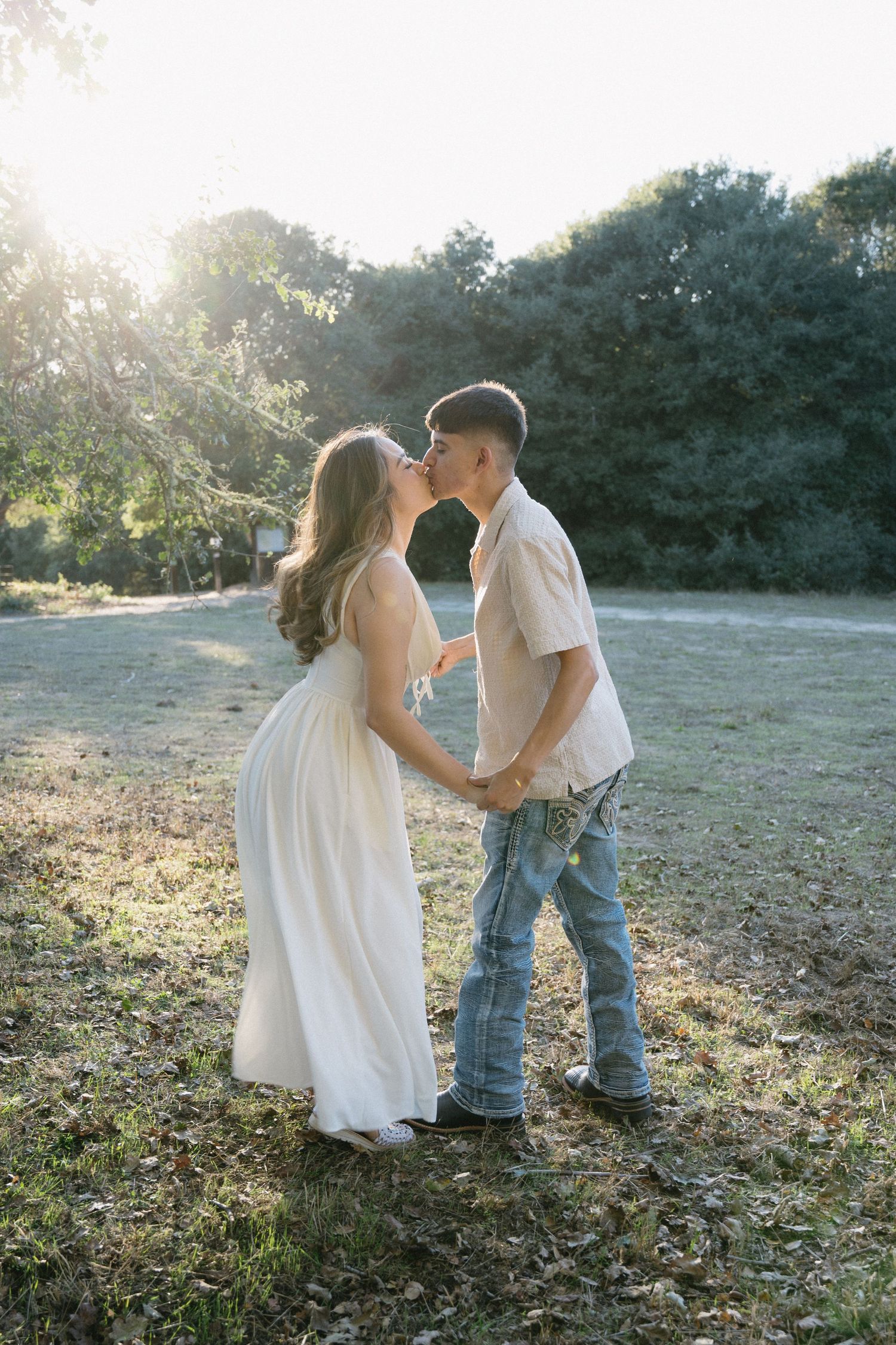 Couple sharing intimate moments in a sunlit outdoor setting.