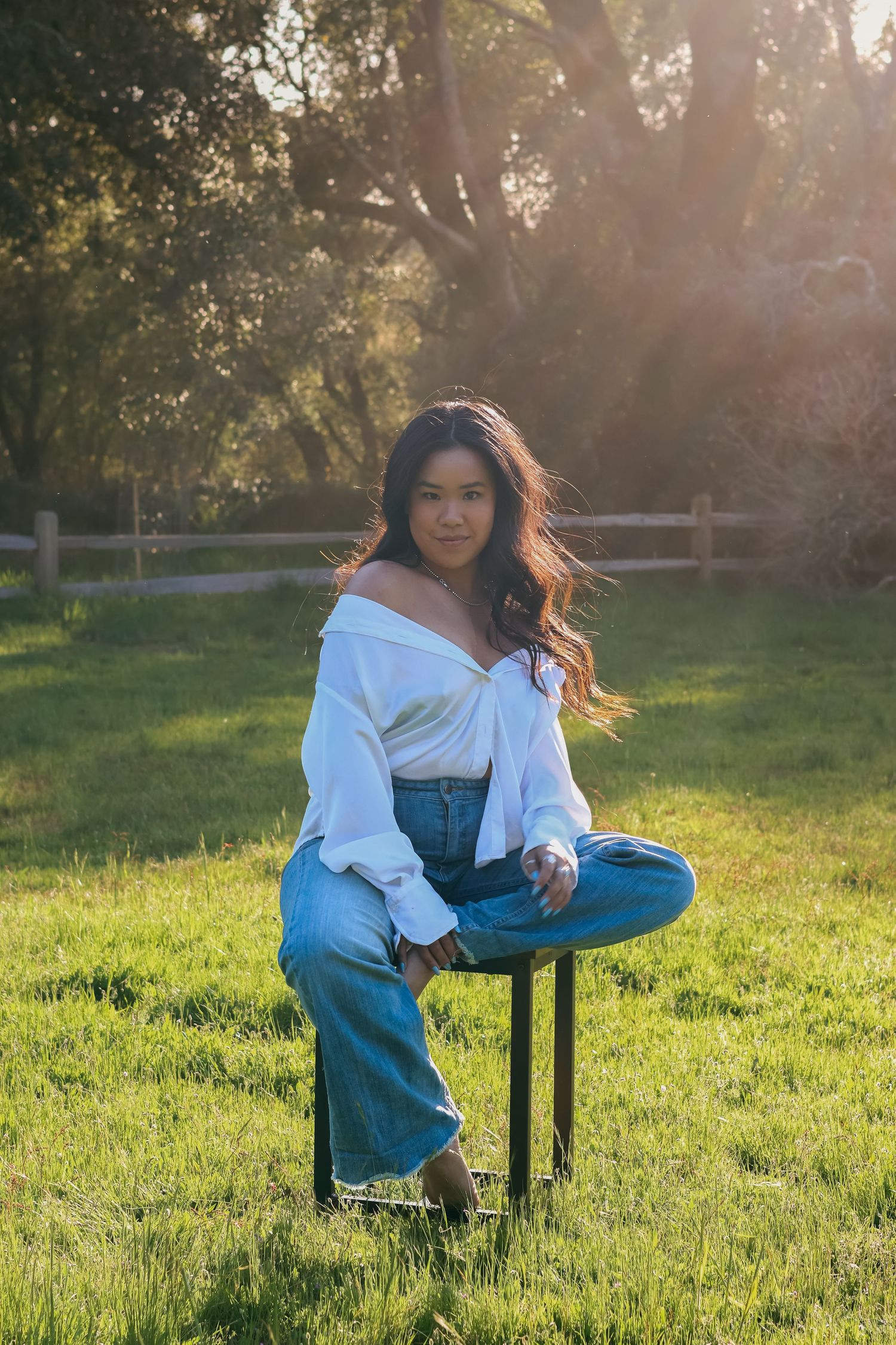 Portrait session in a sunlit field with white top and casual styling.