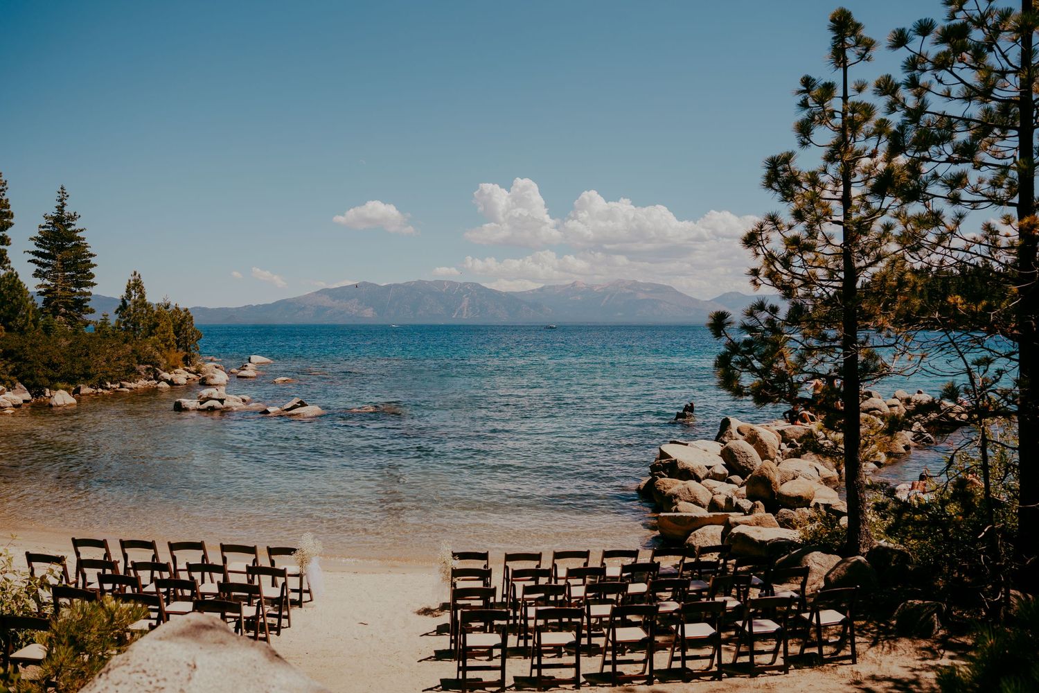 Empty wooden chairs set up for a lakeside wedding ceremony with mountain views.