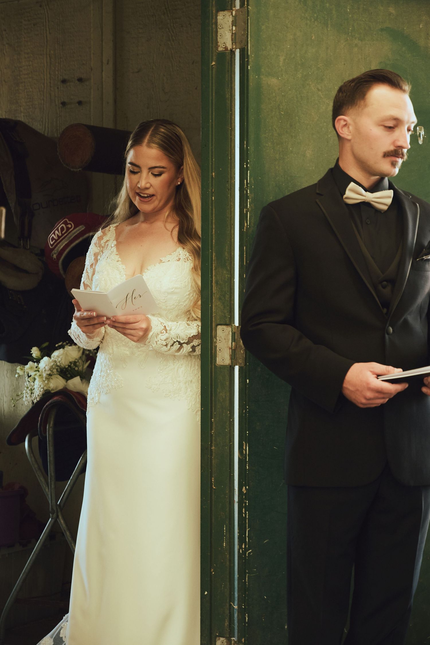 Bride and groom reading wedding vows separately, divided by a green door, bride in lace gown, groom in black tuxedo.
