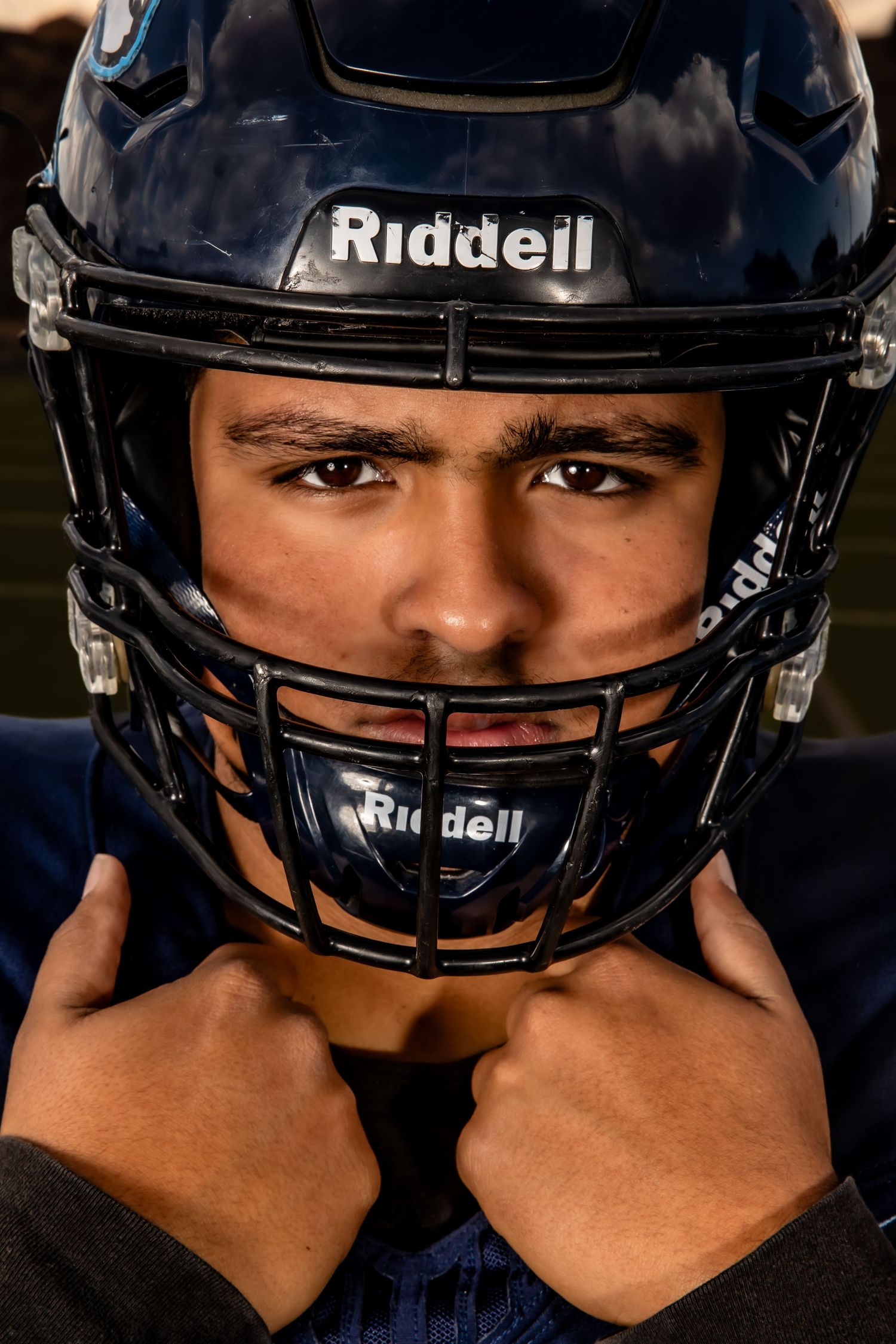 Close-up sequence showing a Riddell football helmet being put on against dark background.